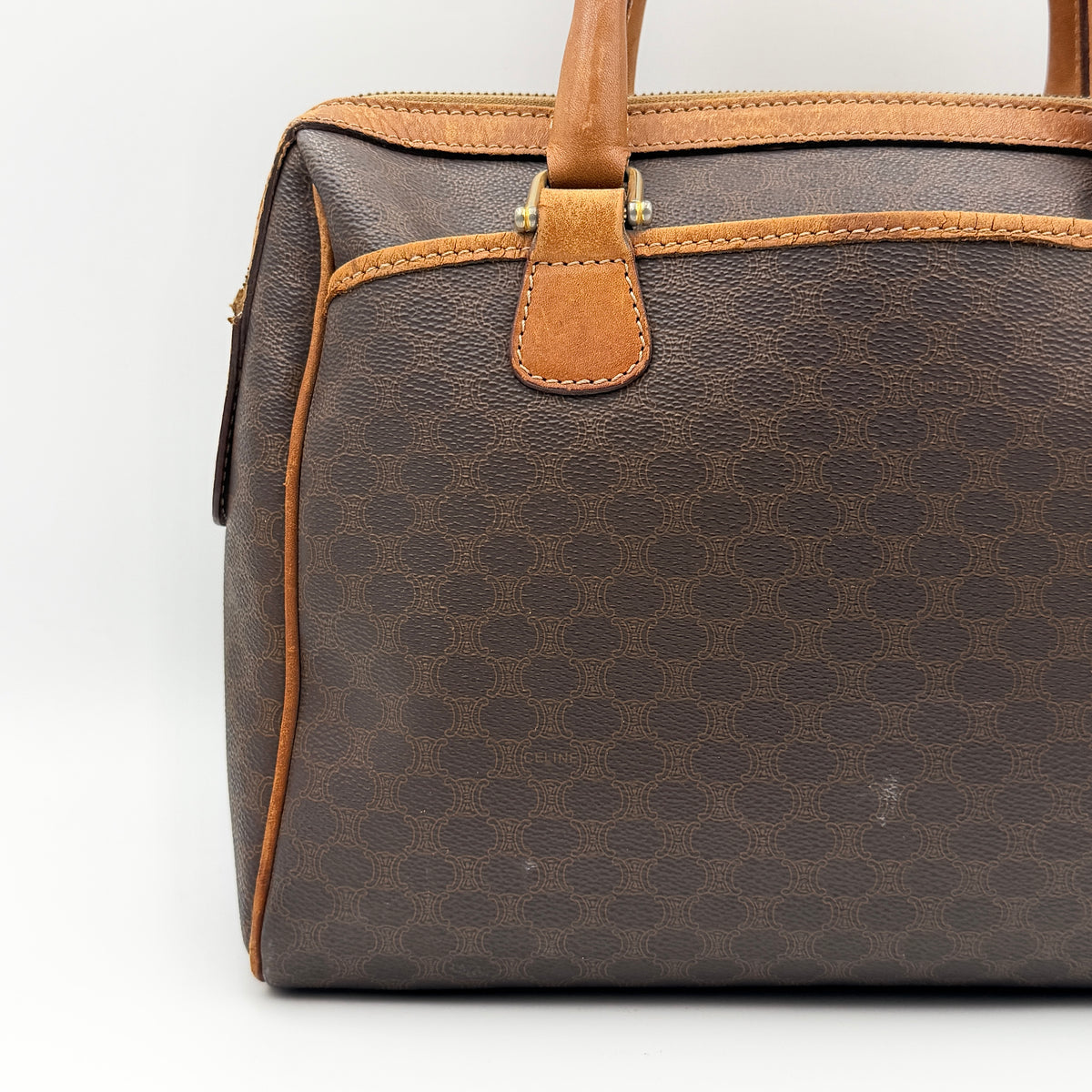 Celine Triomphe Macadam Boston Bag in brown coated canvas with tan leather trim and top handles, photographed against a white background.