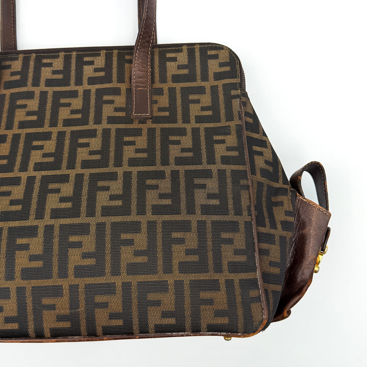 Fendi FF Zucca Double Zip Tote Bag in brown monogram canvas with leather straps and side pocket detail, shown on a yellow dust bag.