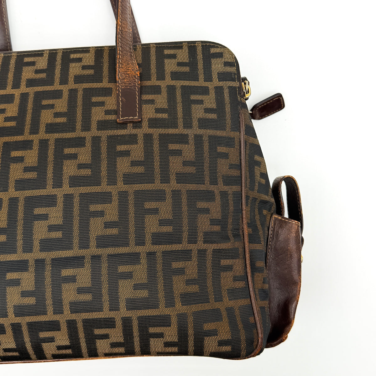 Fendi FF Zucca Double Zip Tote Bag in brown monogram canvas with leather straps and side pocket detail, shown on a yellow dust bag.
