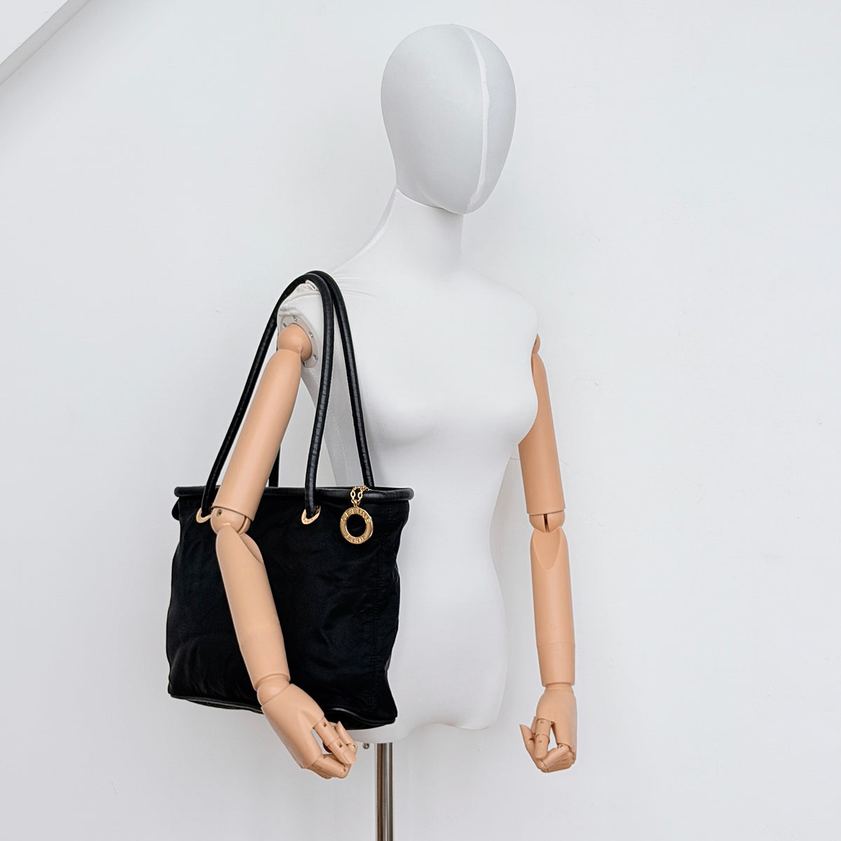 Black Celine nylon tote bag with gold circle logo hardware and leather handles, photographed flat on a white background.