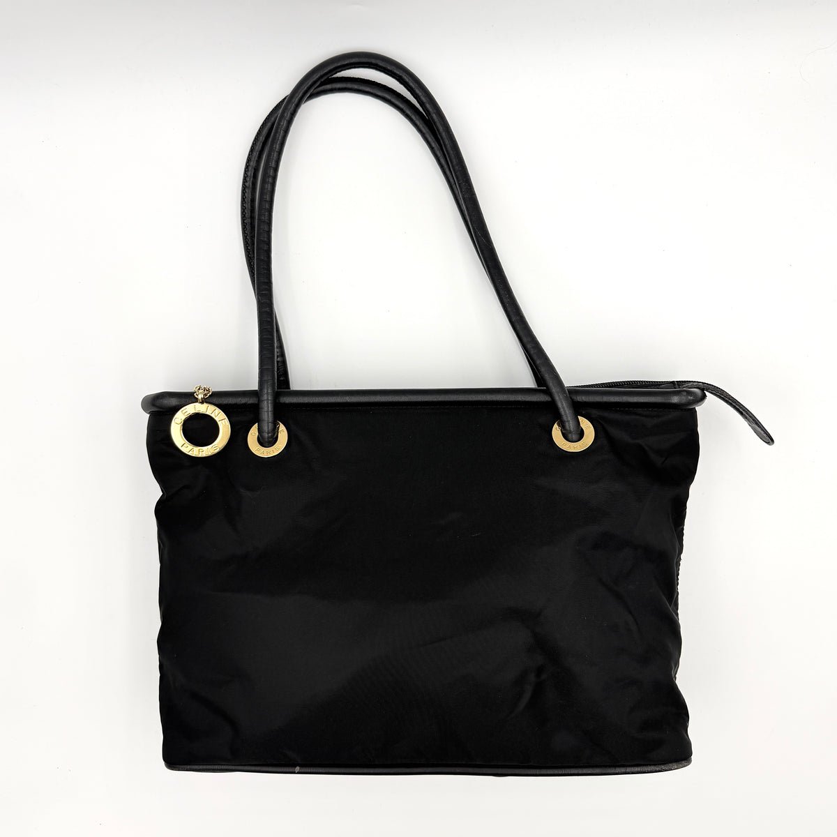 Black Celine nylon tote bag with gold circle logo hardware and leather handles, photographed flat on a white background.