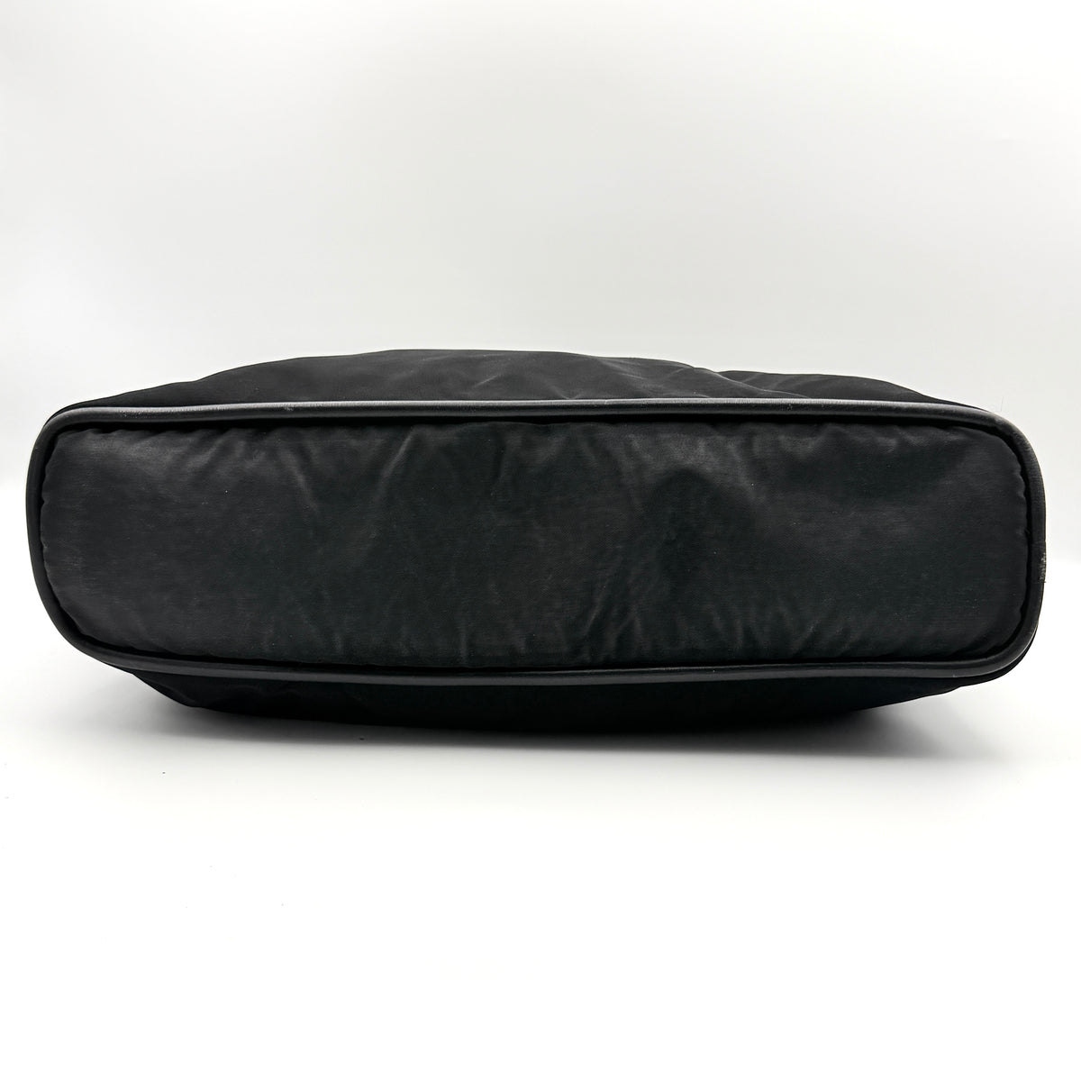 Black Celine nylon tote bag with gold circle logo hardware and leather handles, photographed flat on a white background.