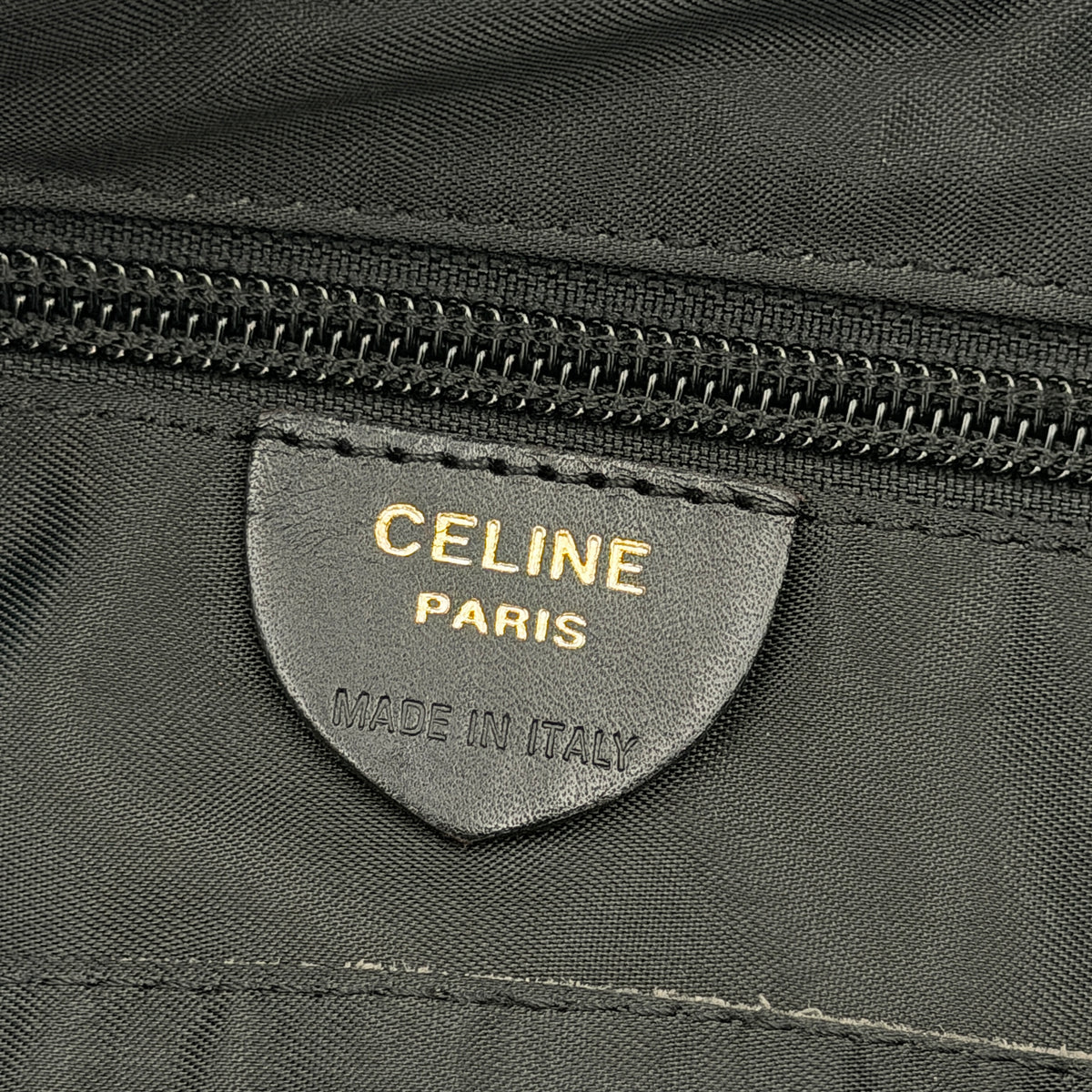 Black Celine nylon tote bag with gold circle logo hardware and leather handles, photographed flat on a white background.