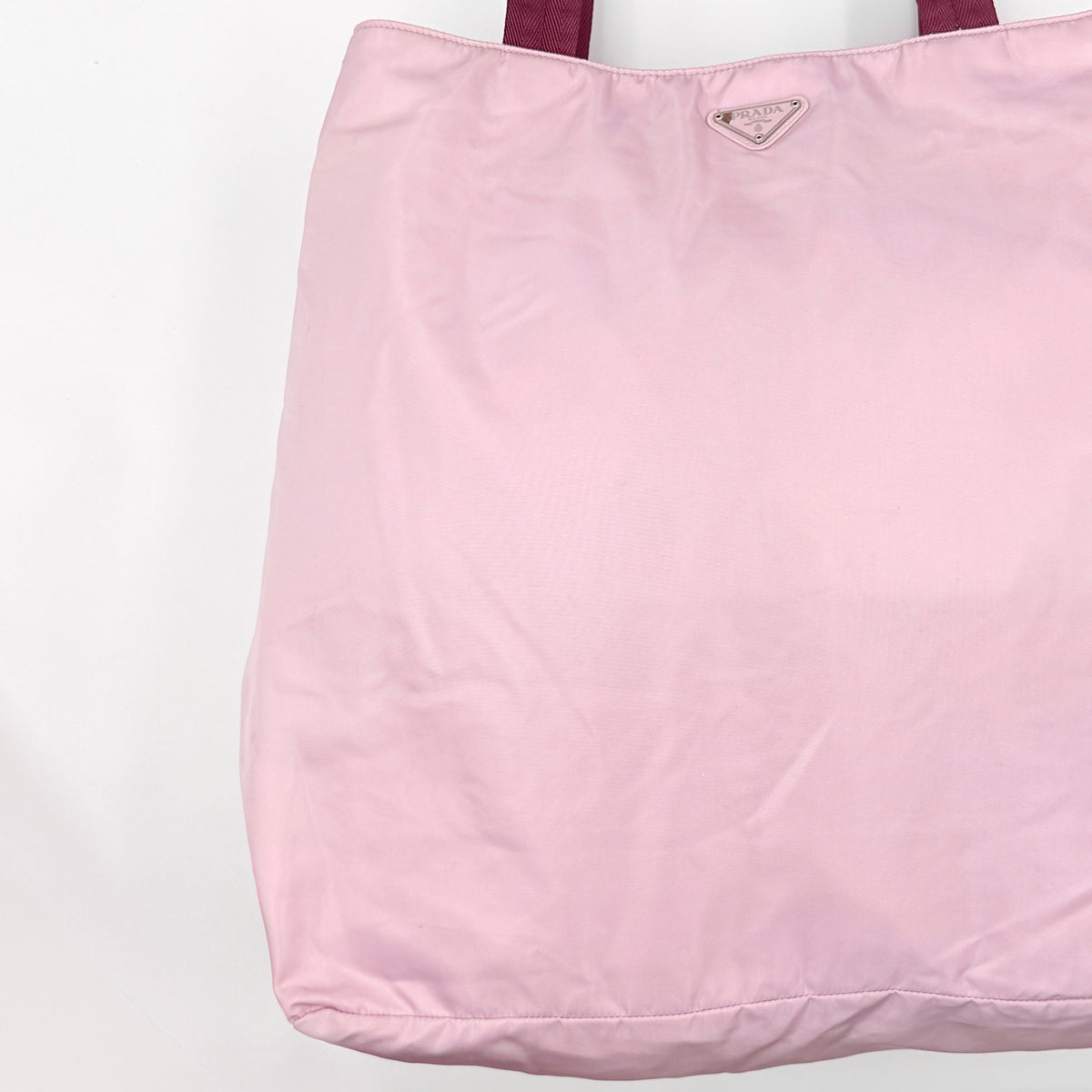 Prada pink nylon tote bag with berry handles photographed against a white background.