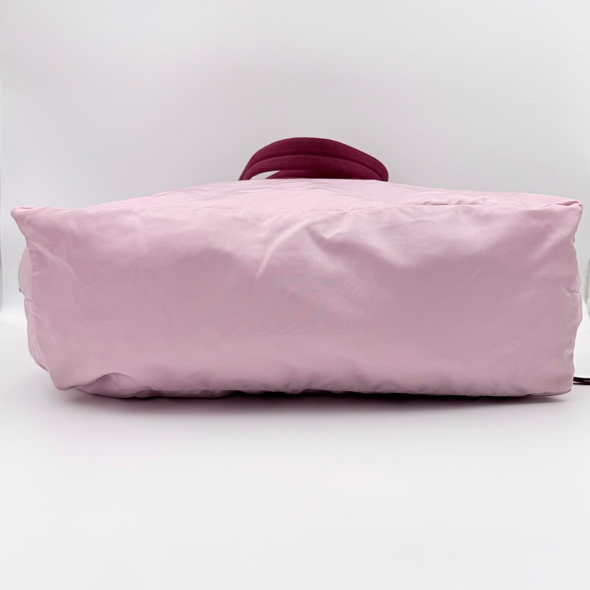 Prada pink nylon tote bag with berry handles photographed against a white background.
