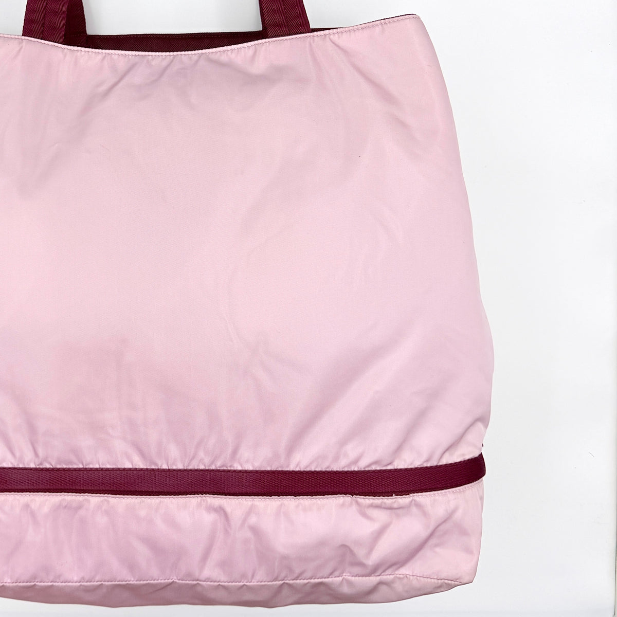 Prada pink nylon tote bag with berry handles photographed against a white background.