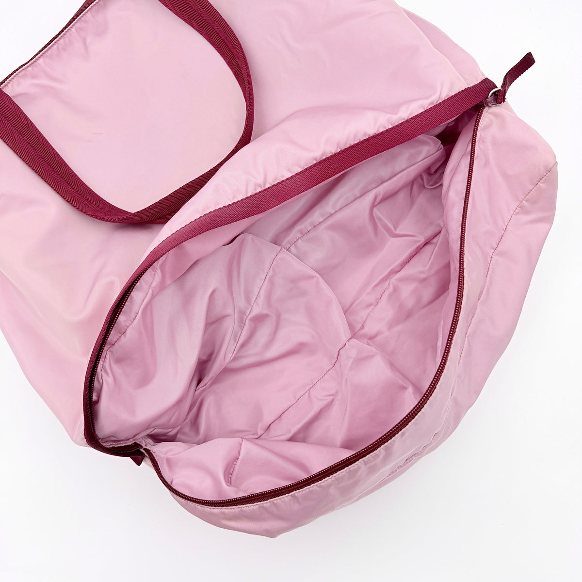 Prada pink nylon tote bag with berry handles photographed against a white background.