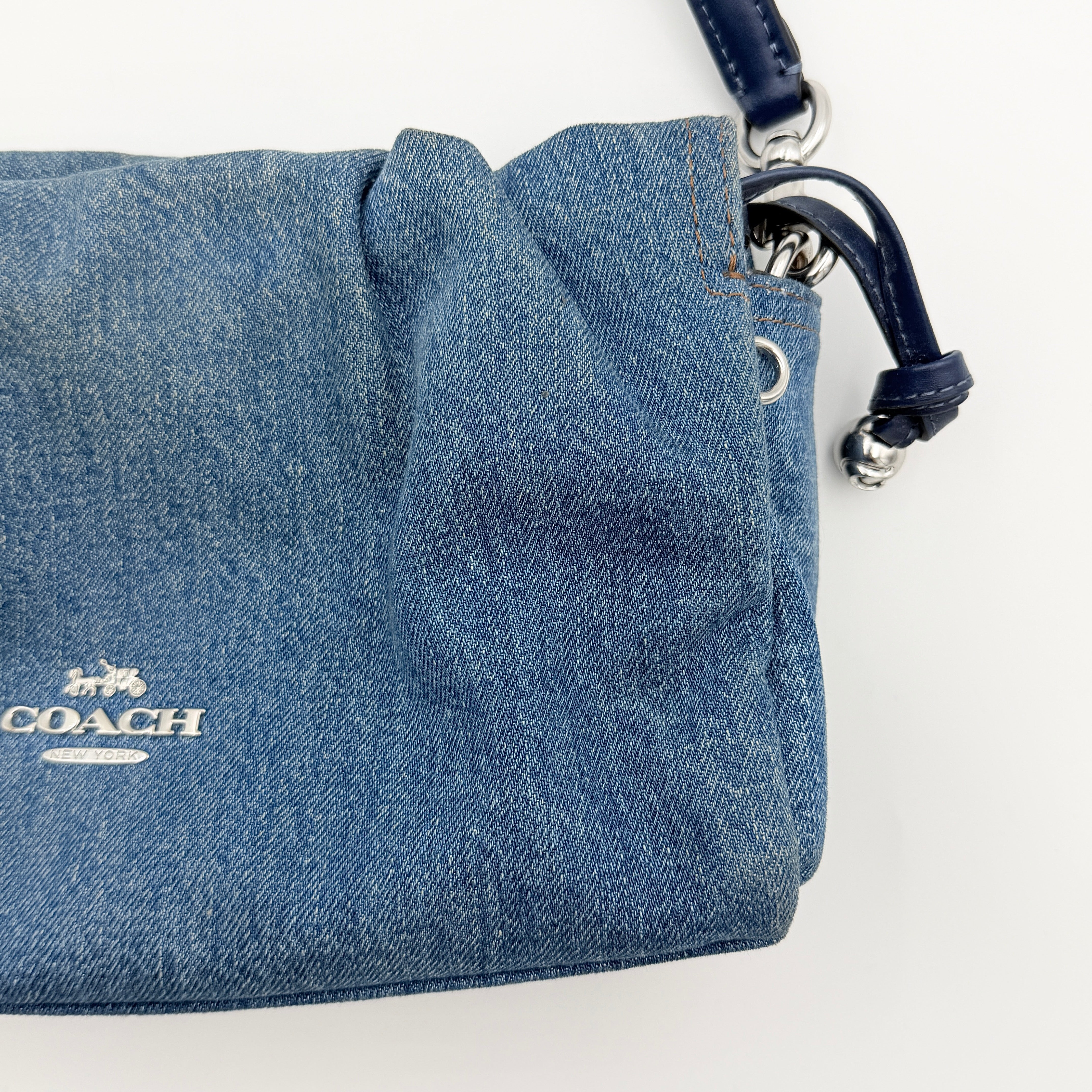 Coach Faye Shoulder Bag in blue denim with navy leather strap and detachable crossbody, styled simply against a white background.