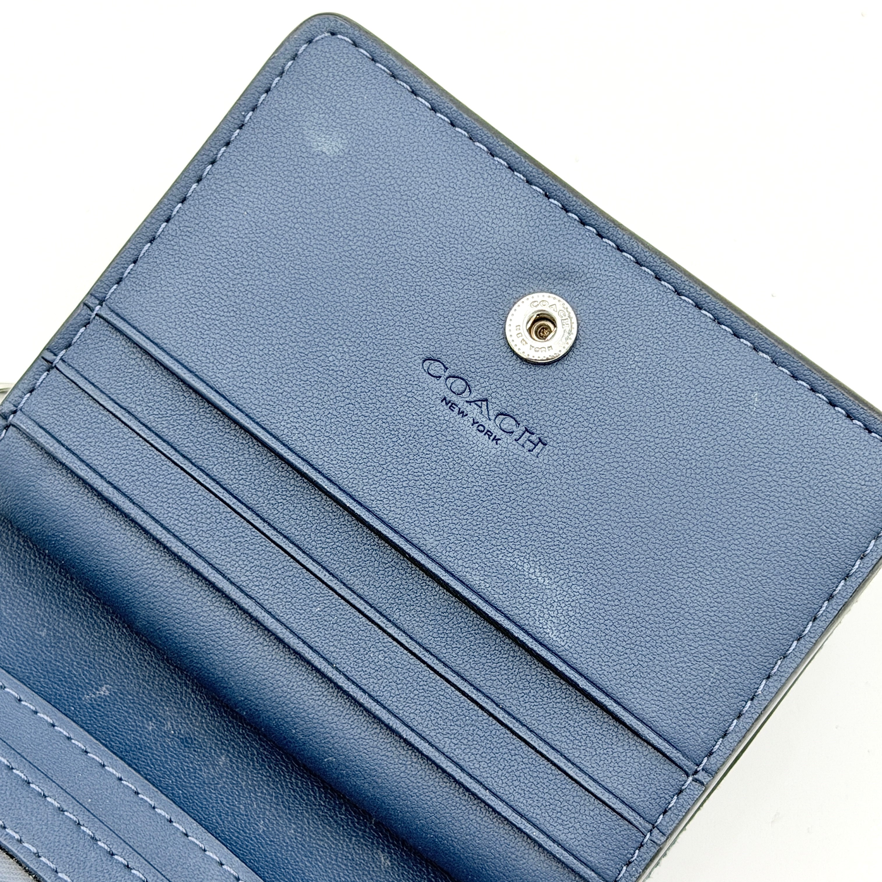 Coach Signature Snap Wallet in blue denim with silver-tone logo, shown closed from the front.