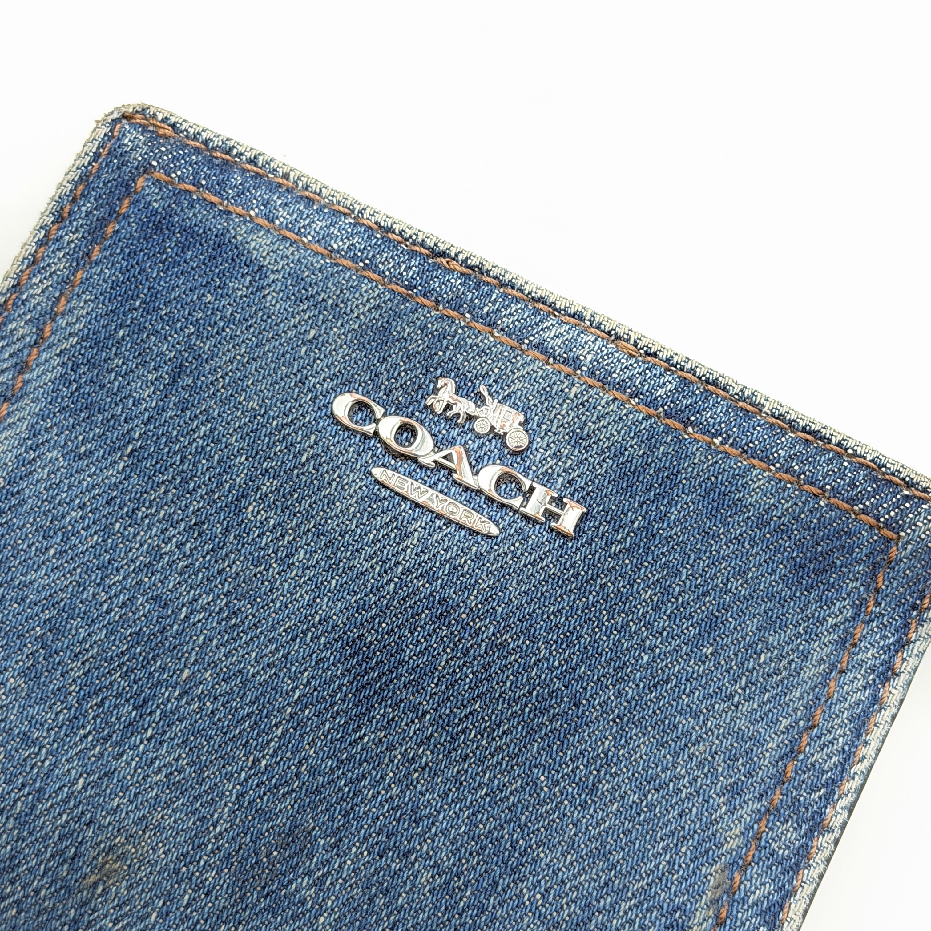 Coach Signature Snap Wallet in blue denim with silver-tone logo, shown closed from the front.