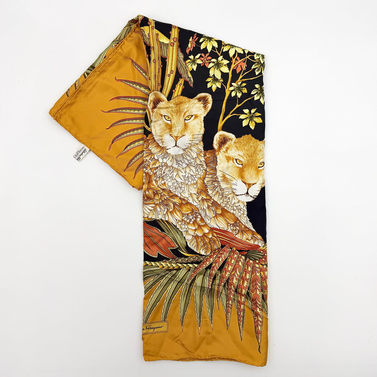 Salvatore Ferragamo silk scarf in gold and black with detailed lion and jungle botanical print.