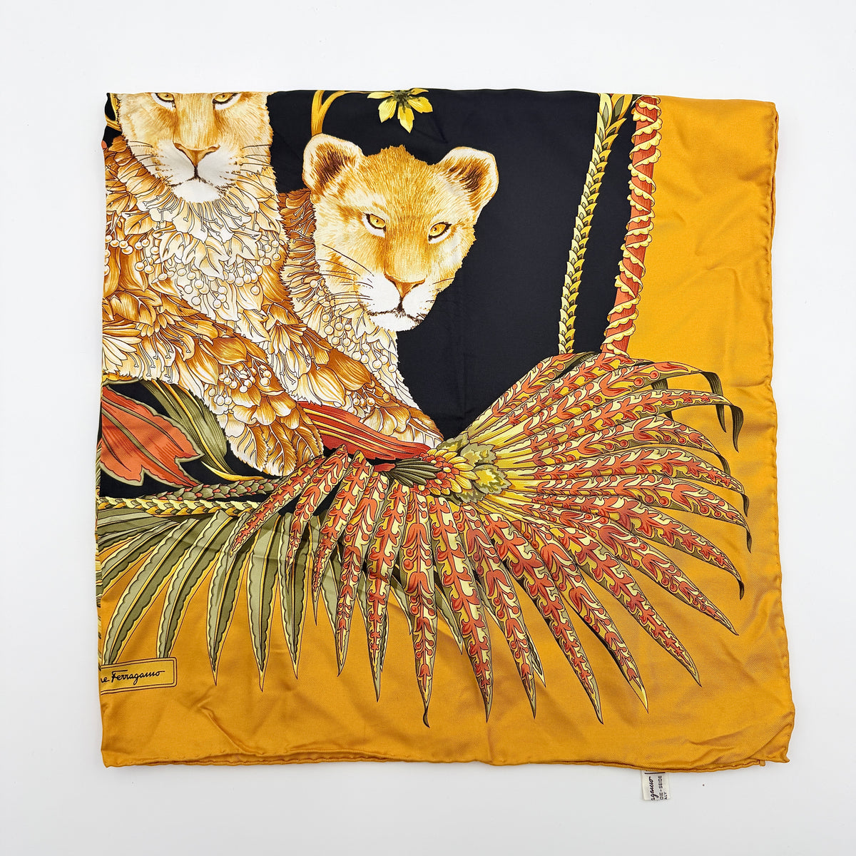 Salvatore Ferragamo silk scarf in gold and black with detailed lion and jungle botanical print.