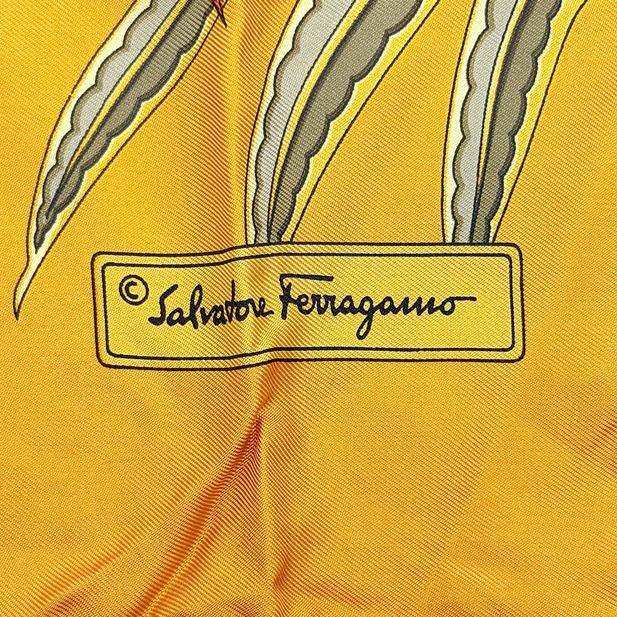 Salvatore Ferragamo silk scarf in gold and black with detailed lion and jungle botanical print.