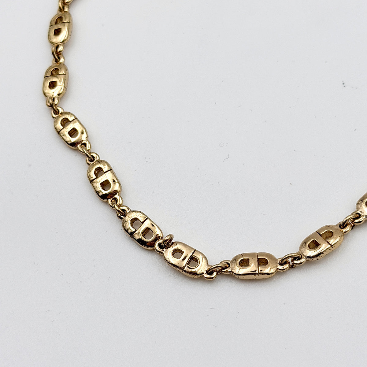 Christian Dior gold CD logo link choker necklace displayed on its original box.