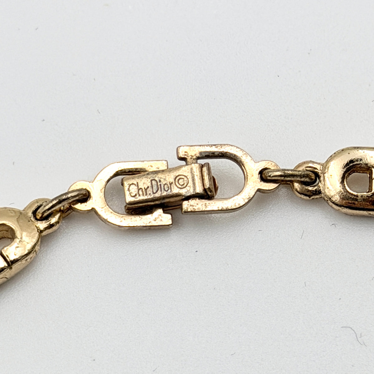 Christian Dior gold CD logo link choker necklace displayed on its original box.
