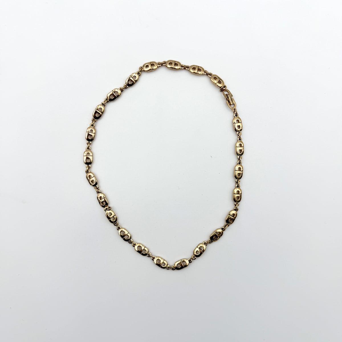 Christian Dior gold CD logo link choker necklace displayed on its original box.