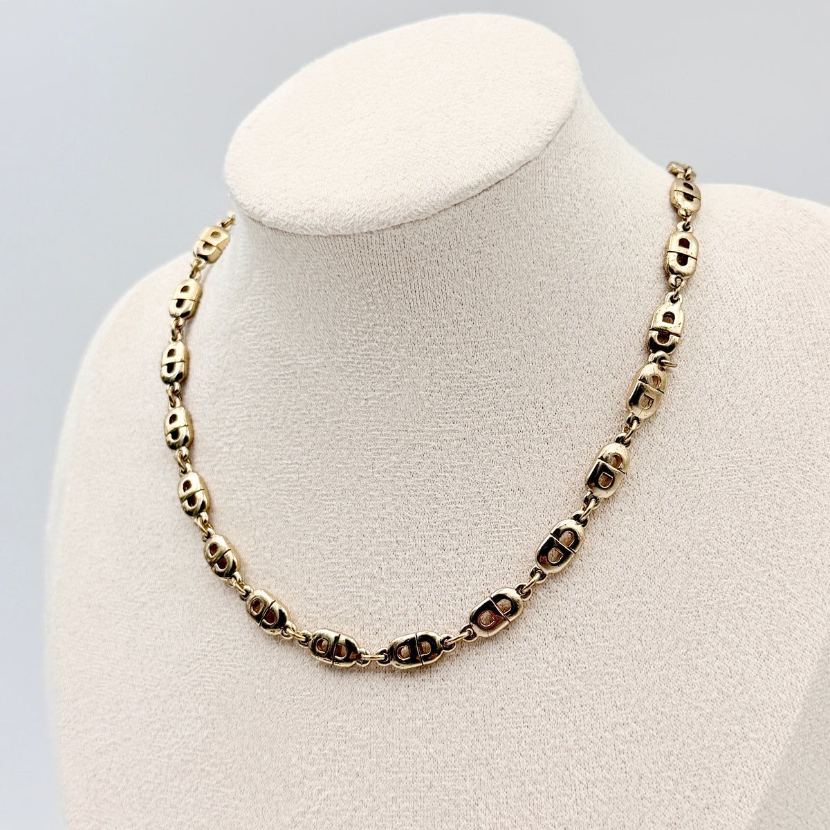 Christian Dior gold CD logo link choker necklace displayed on its original box.