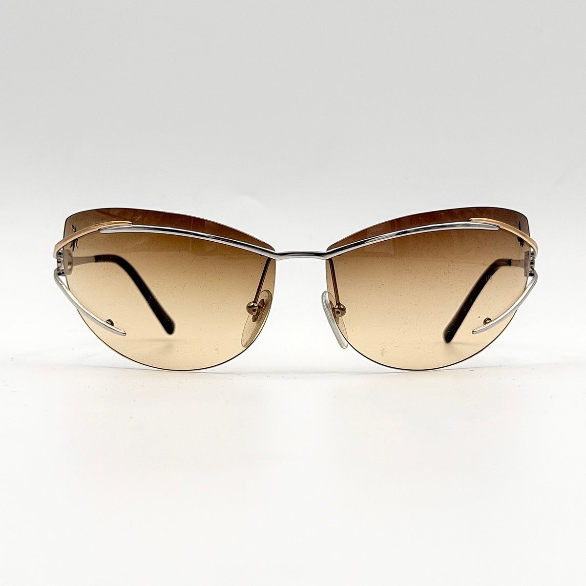 Salvatore Ferragamo rimless sunglasses with gradient brown lenses and sculptural Gancini metal arms on a white background.