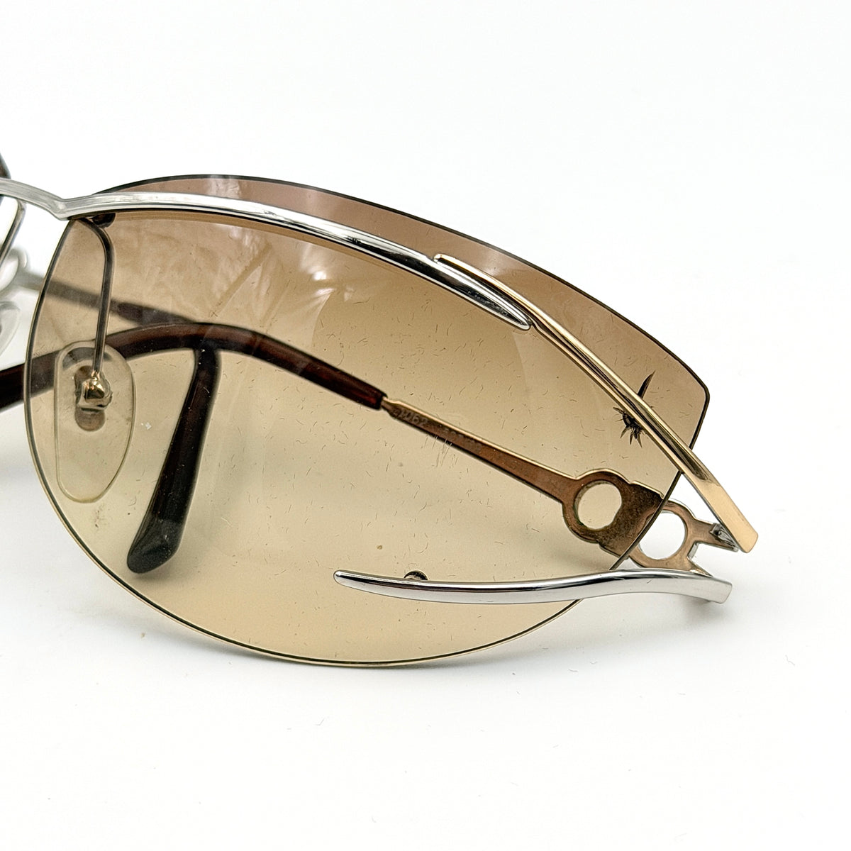Salvatore Ferragamo rimless sunglasses with gradient brown lenses and sculptural Gancini metal arms on a white background.