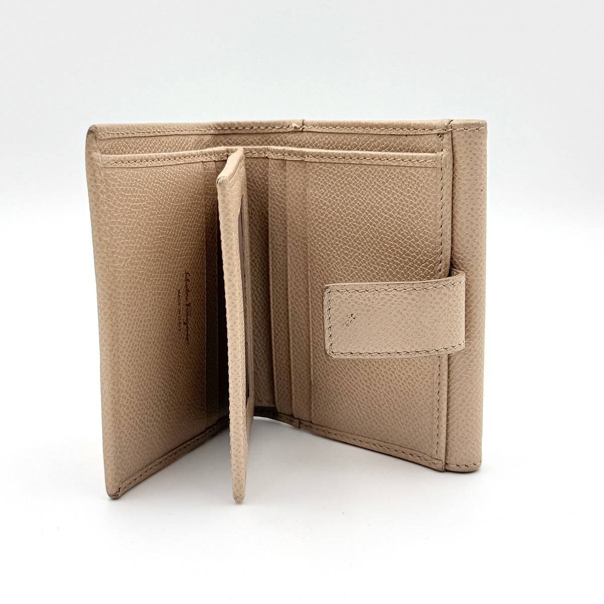 Salvatore Ferragamo beige grained leather compact bifold wallet with gold Gancini hardware, photographed on a white background.
