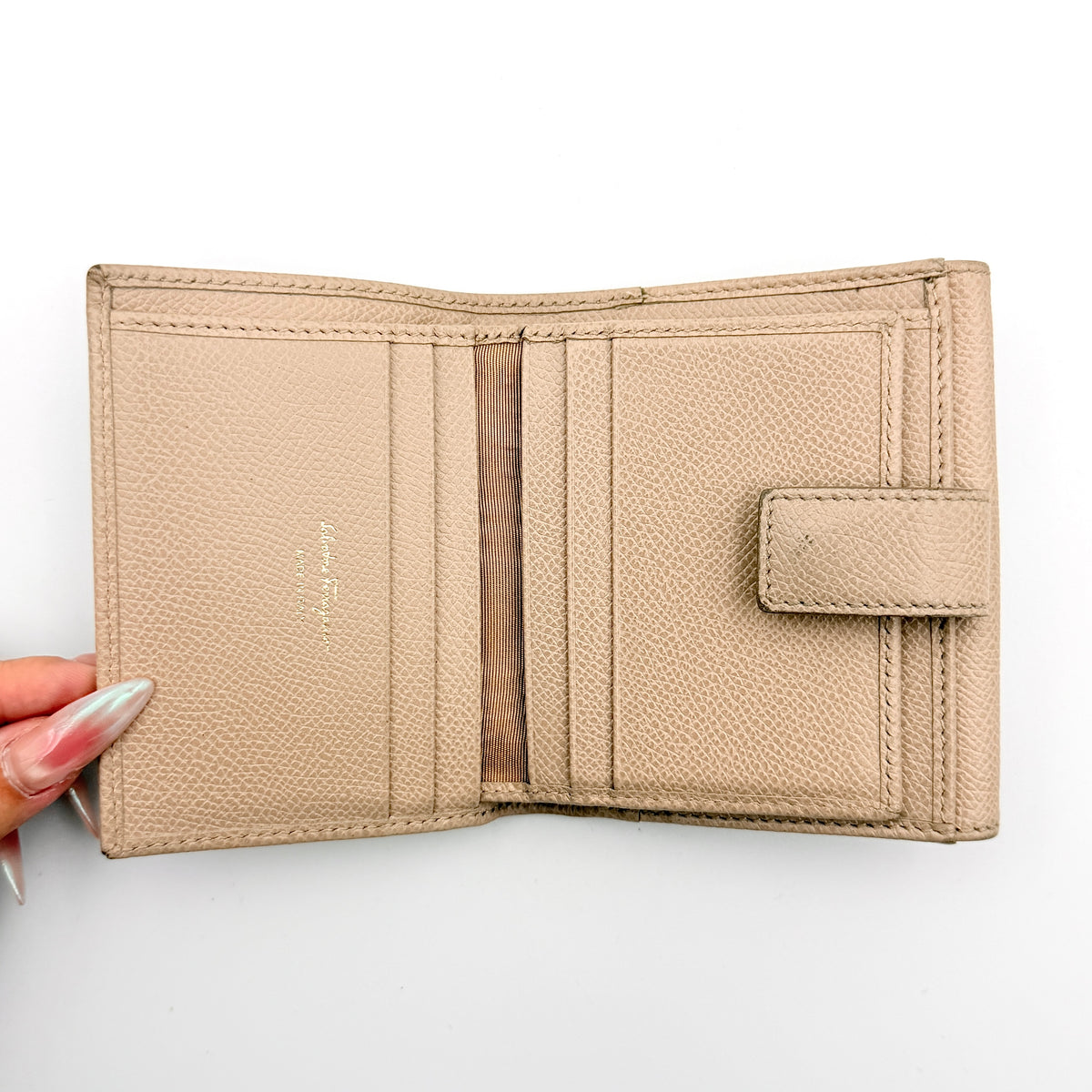 Salvatore Ferragamo beige grained leather compact bifold wallet with gold Gancini hardware, photographed on a white background.