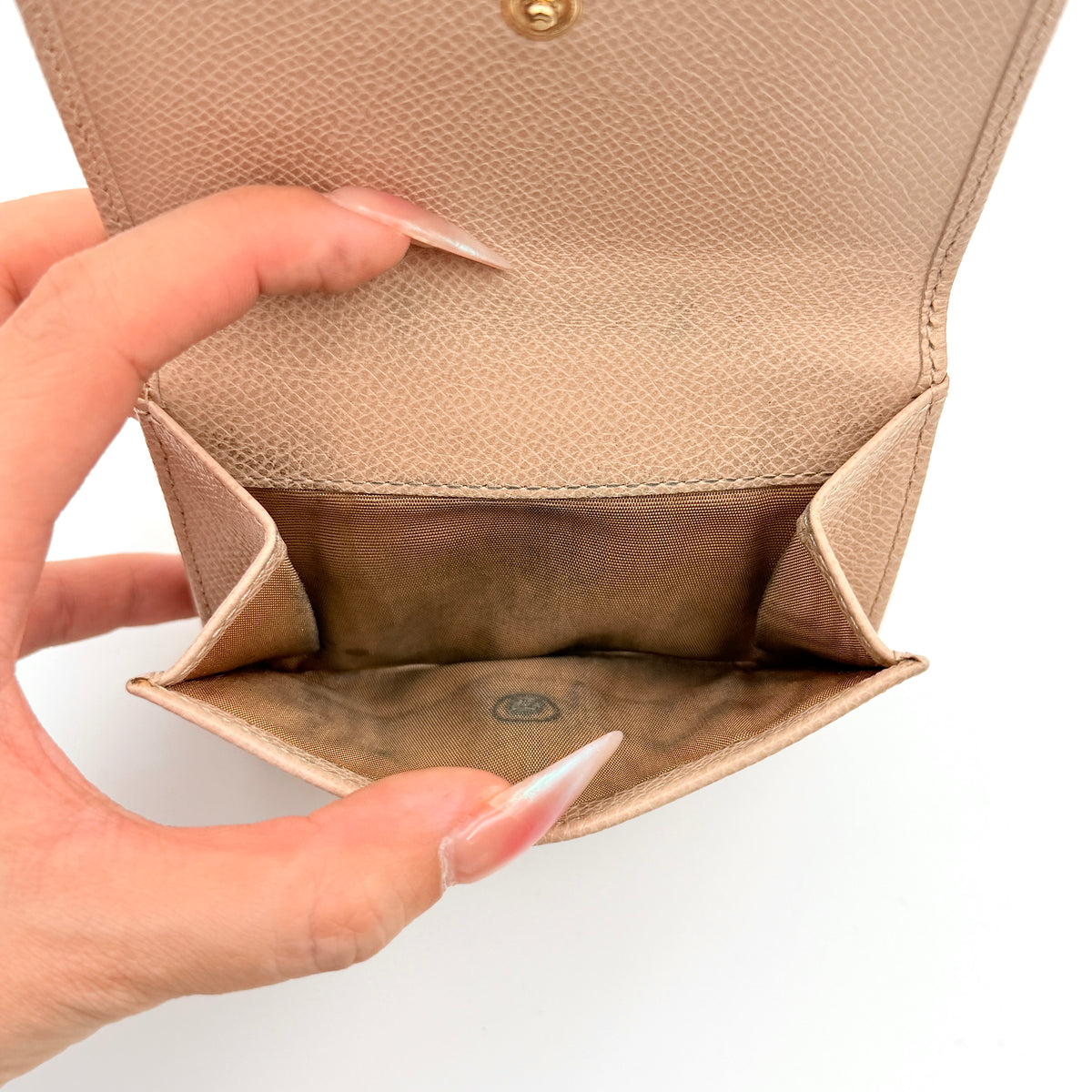 Salvatore Ferragamo beige grained leather compact bifold wallet with gold Gancini hardware, photographed on a white background.