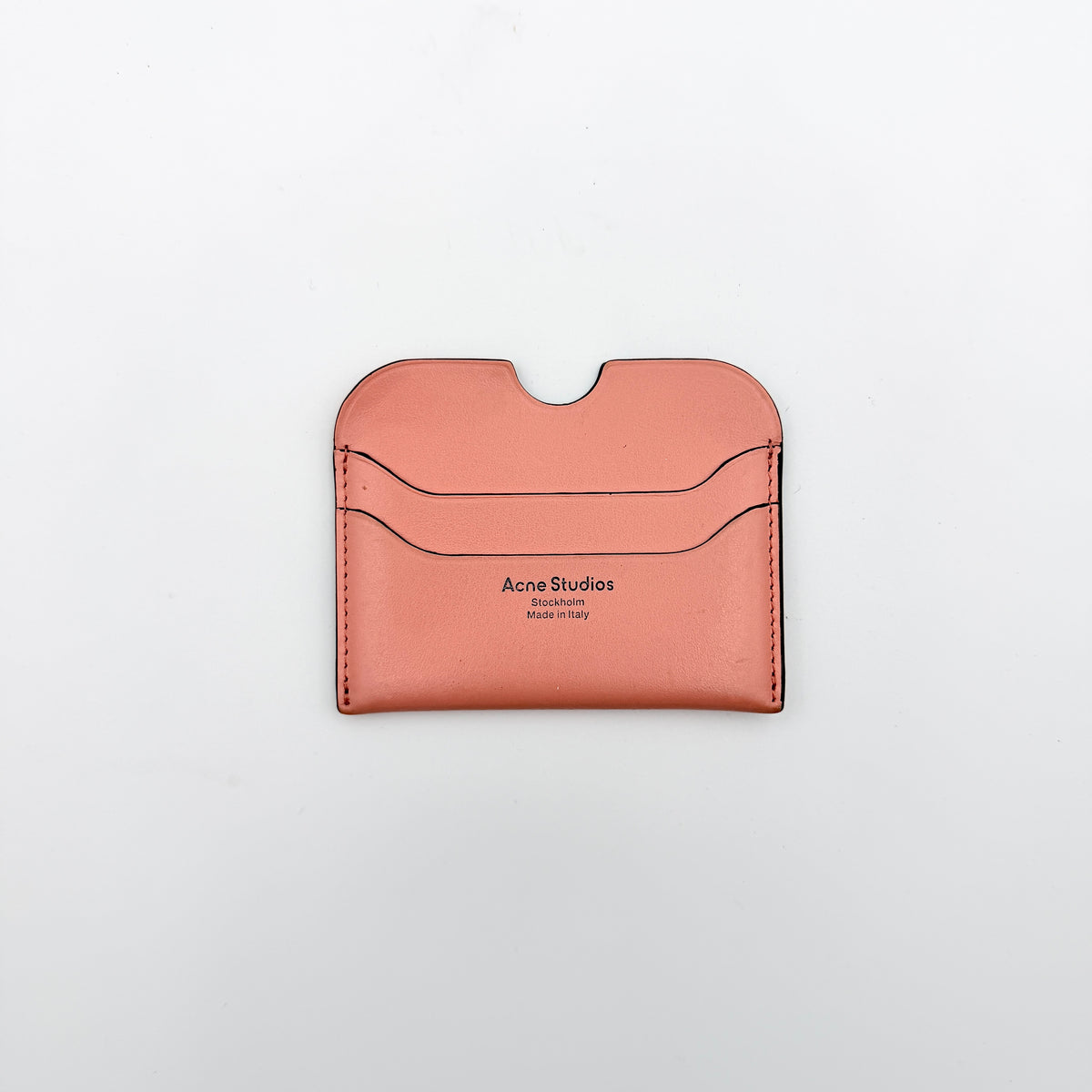 Acne Studios pink leather card holder with embossed logo and double card slots, shown against a clean white background.