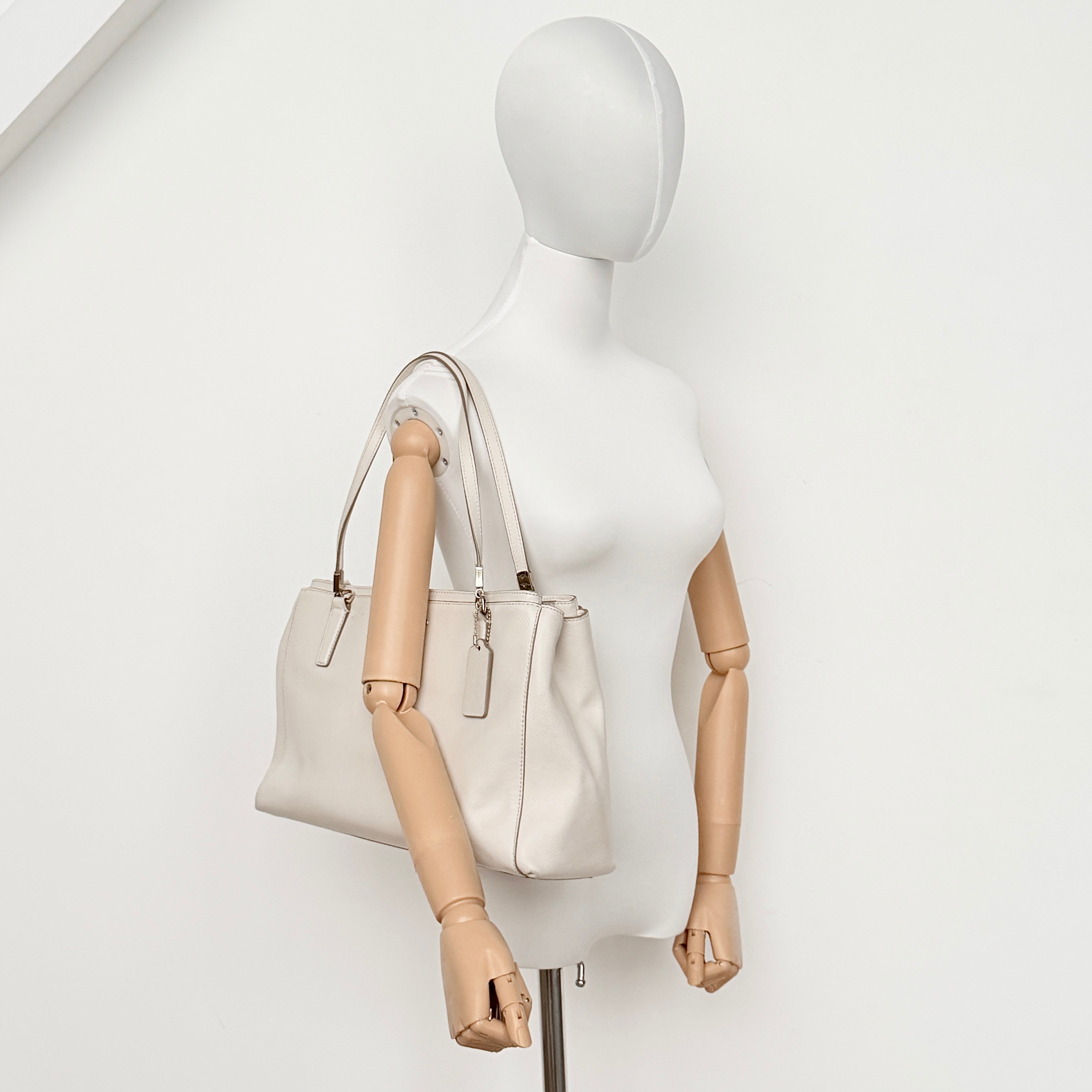 Coach Parker 16 shoulder bag in white leather with dual top handles and gold-tone accents, displayed against a clean background.