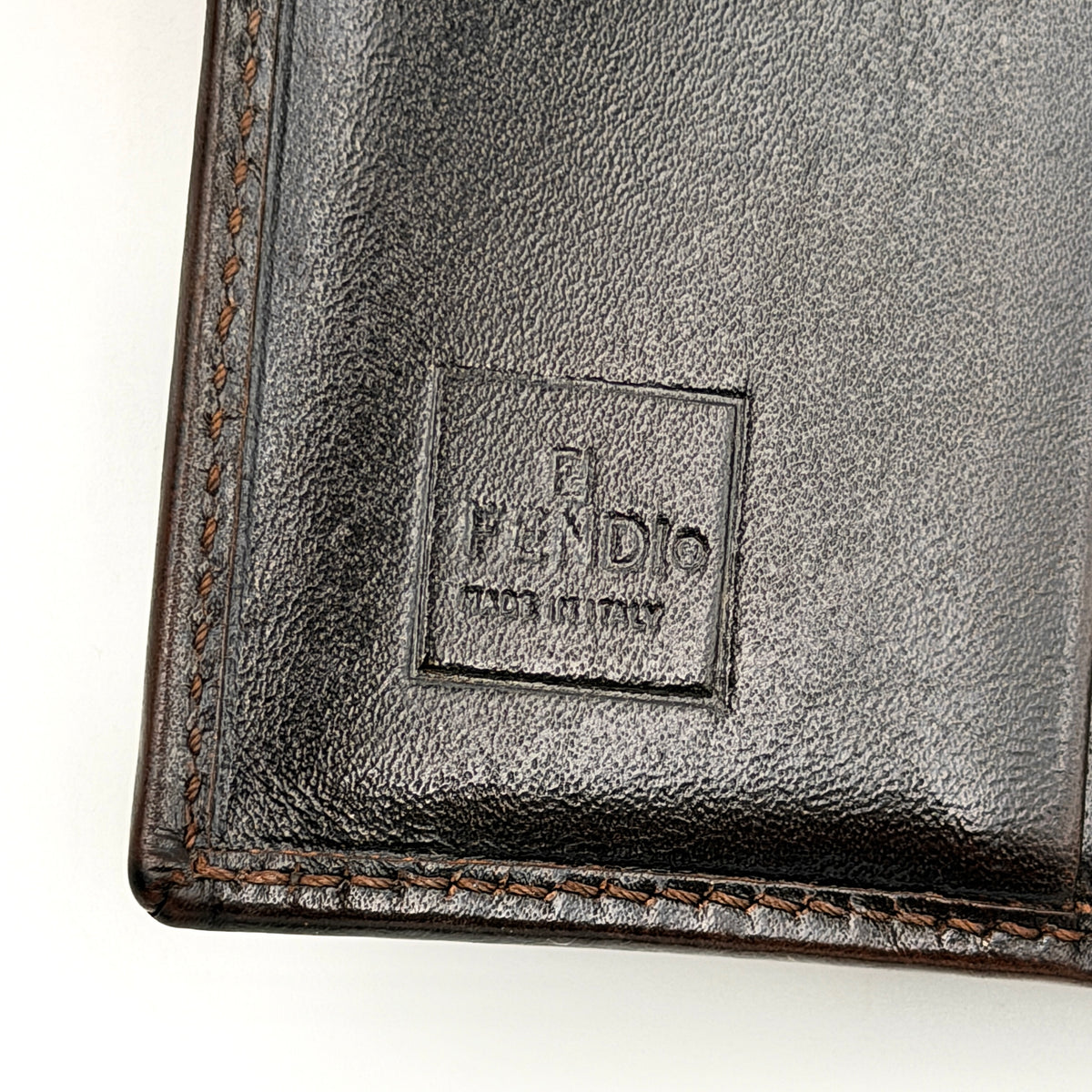 Fendi FF Zucca Monogram bifold wallet in brown and black leather with snap closure, photographed on a white background.