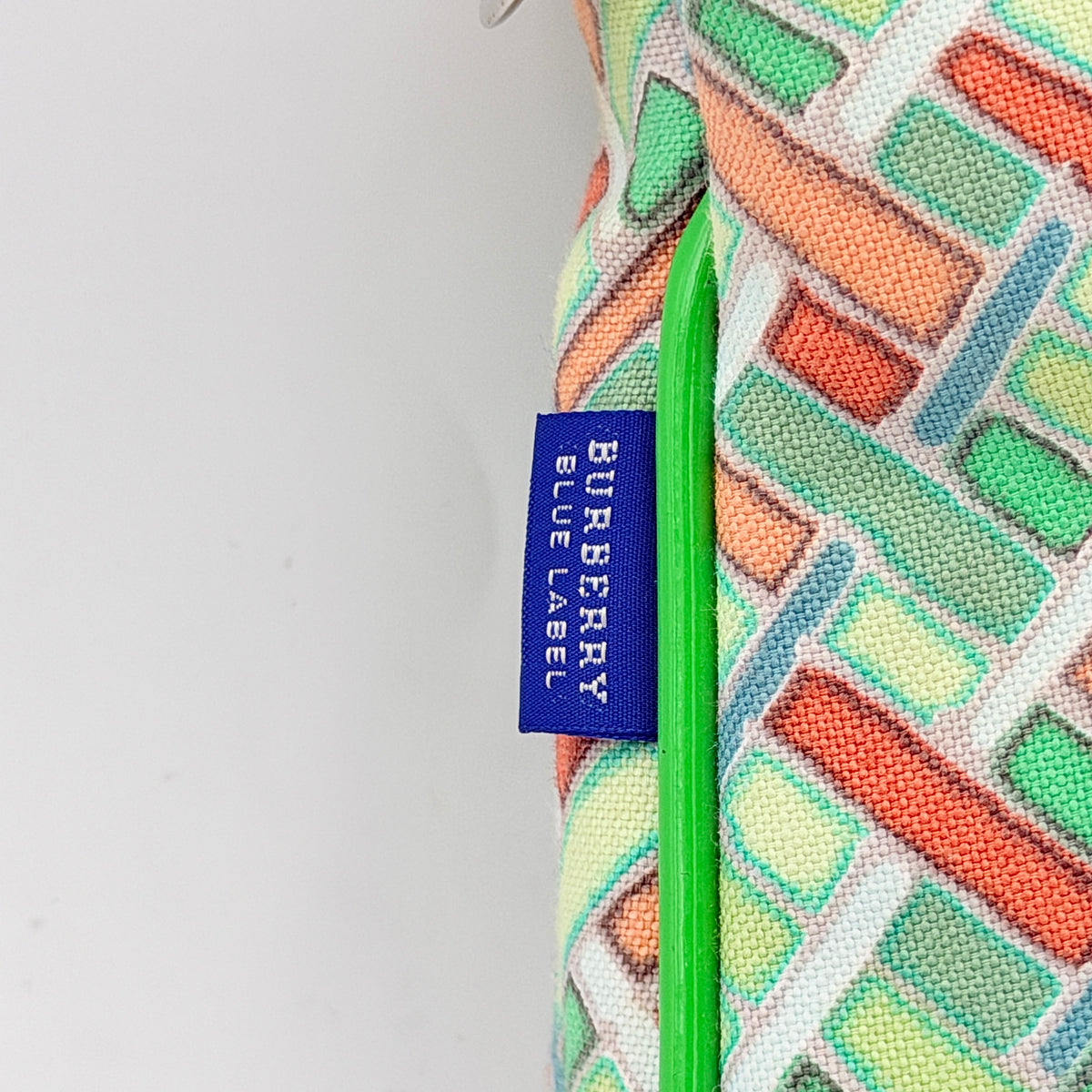 Burberry Blue Label geometric pouch in multicolor canvas with green trim and zip closure, photographed against a clean white background.