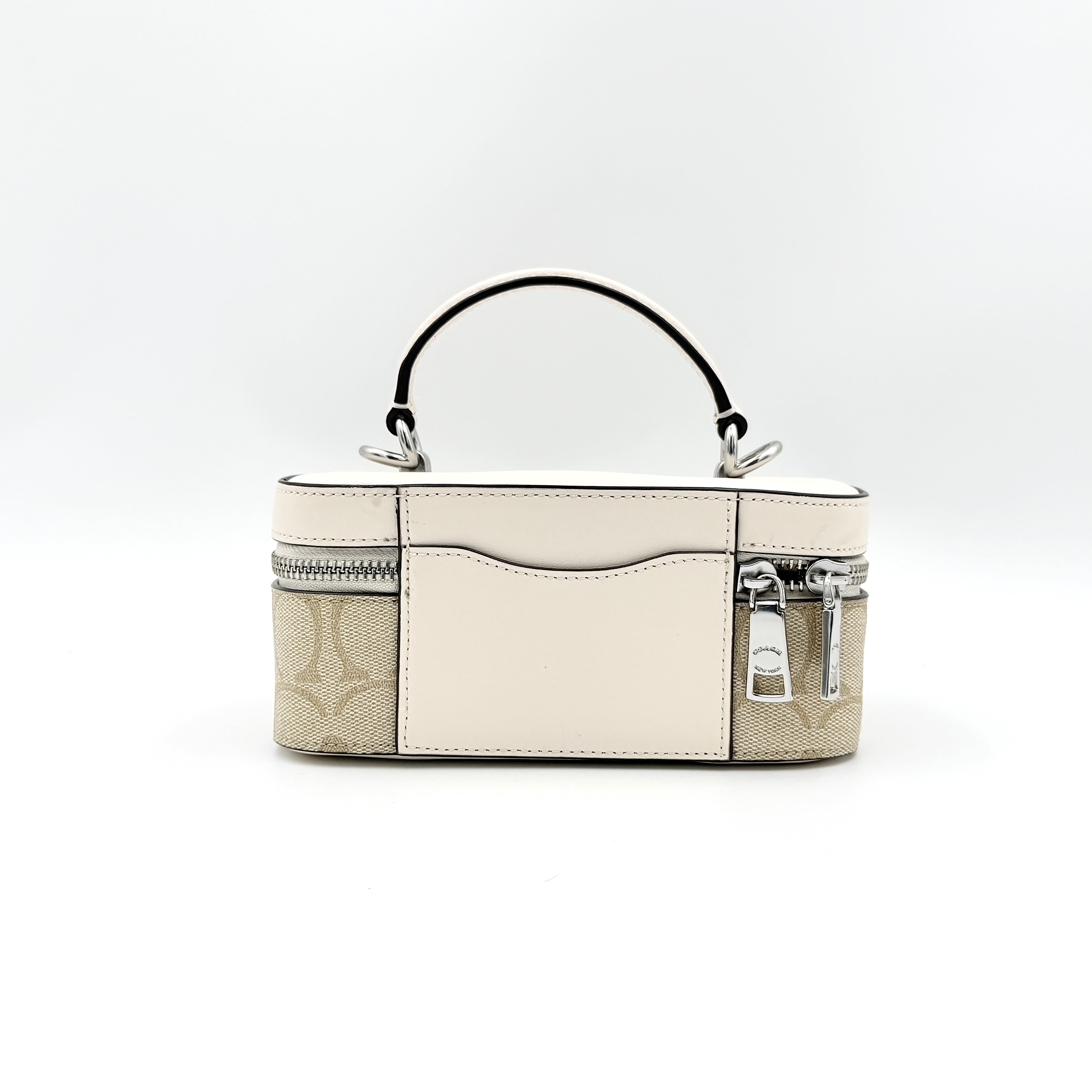 Coach 2Way Signature Train Case in beige and white canvas with a leather top handle and detachable strap, shown with silver zip hardware.