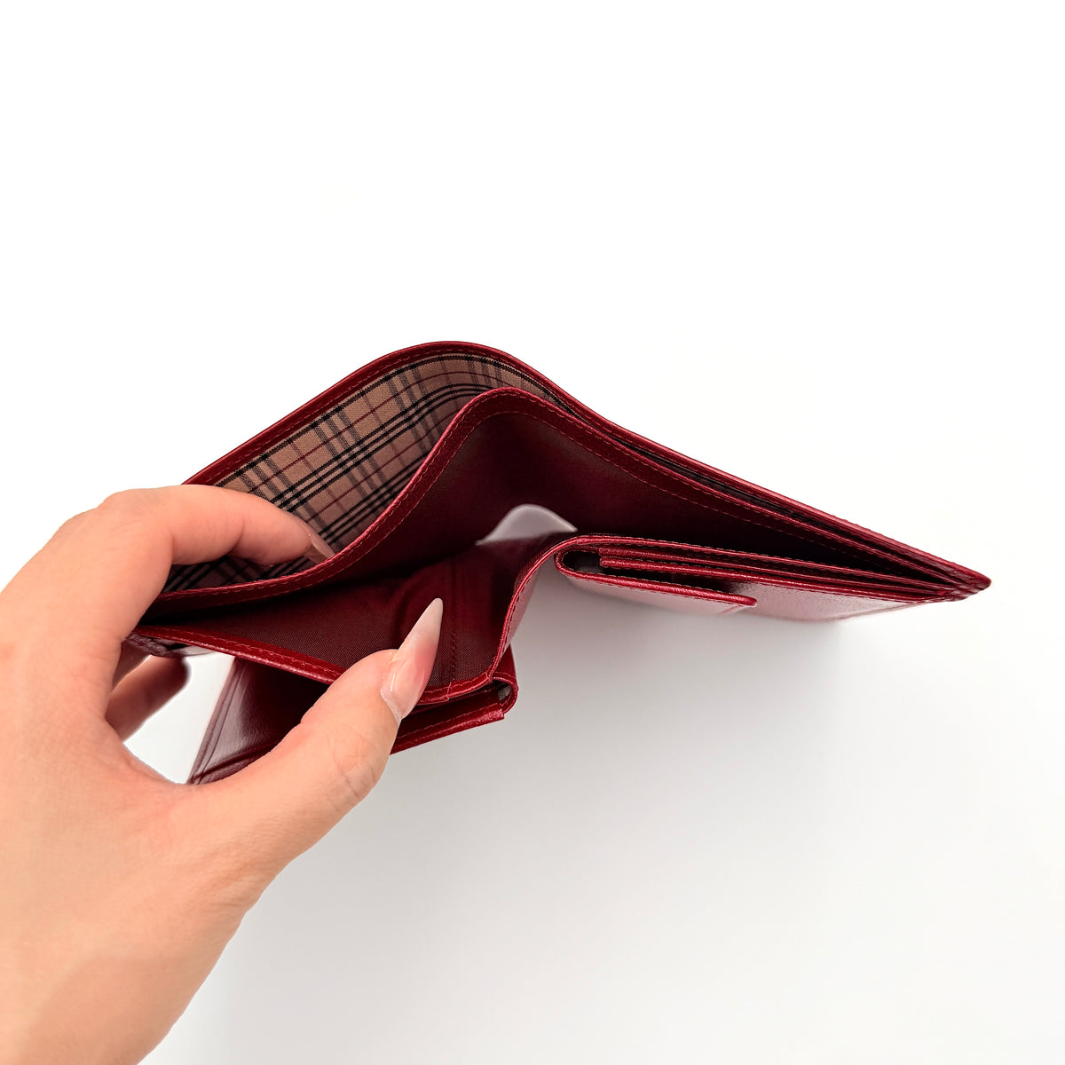 Burberry Nova Check bifold wallet in grained red leather with signature tartan interior, shown closed against a white background