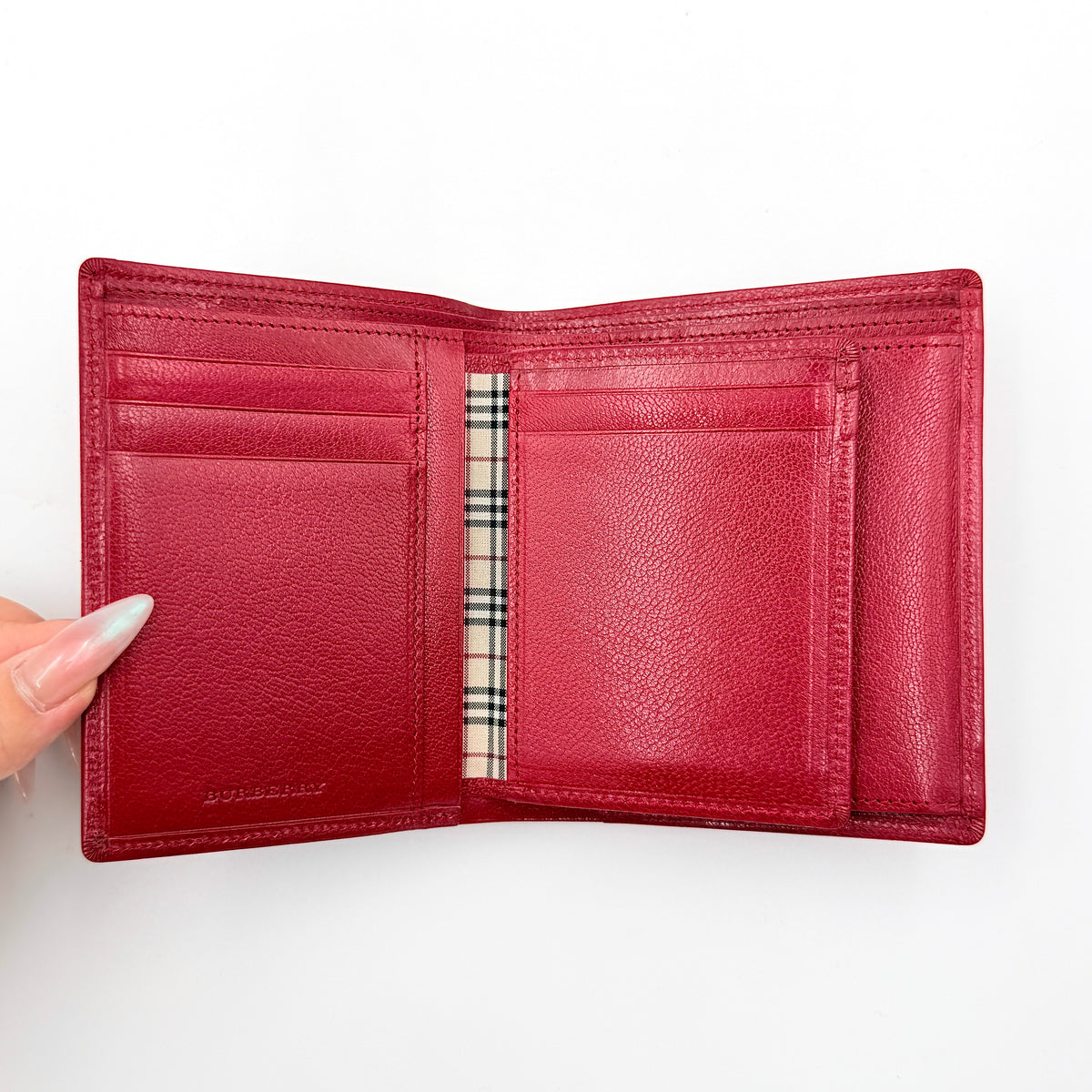 Burberry Nova Check bifold wallet in grained red leather with signature tartan interior, shown closed against a white background