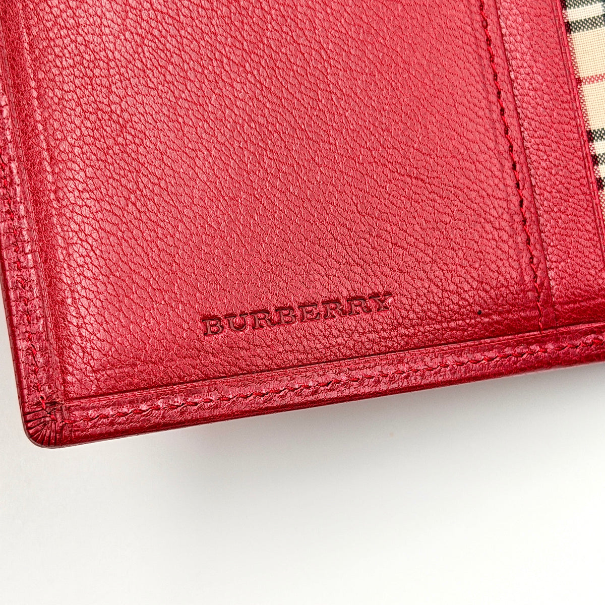 Burberry Nova Check bifold wallet in grained red leather with signature tartan interior, shown closed against a white background