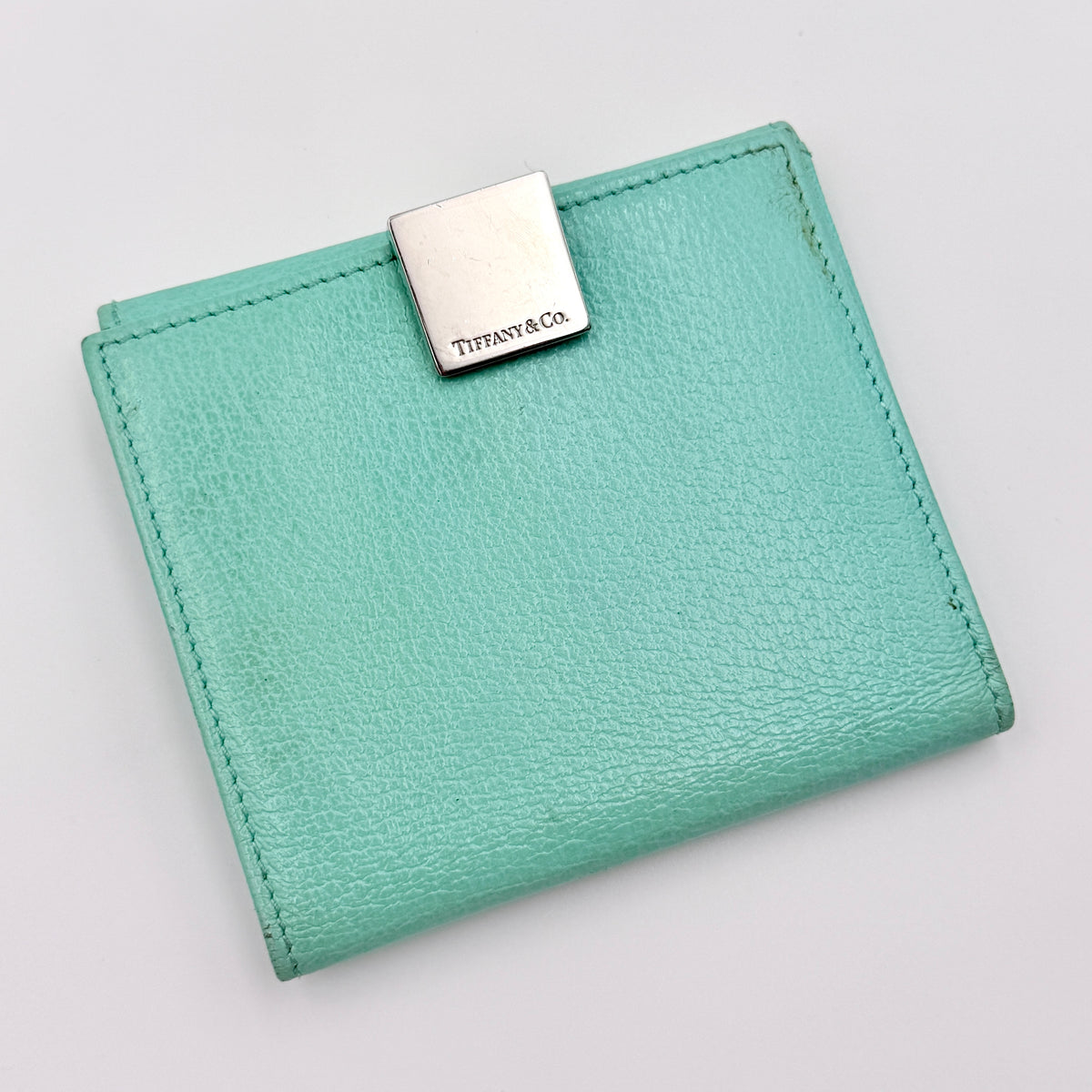 Tiffany & Co. bifold compact wallet in Tiffany Blue leather with silver-tone clasp, photographed on a clean white background.