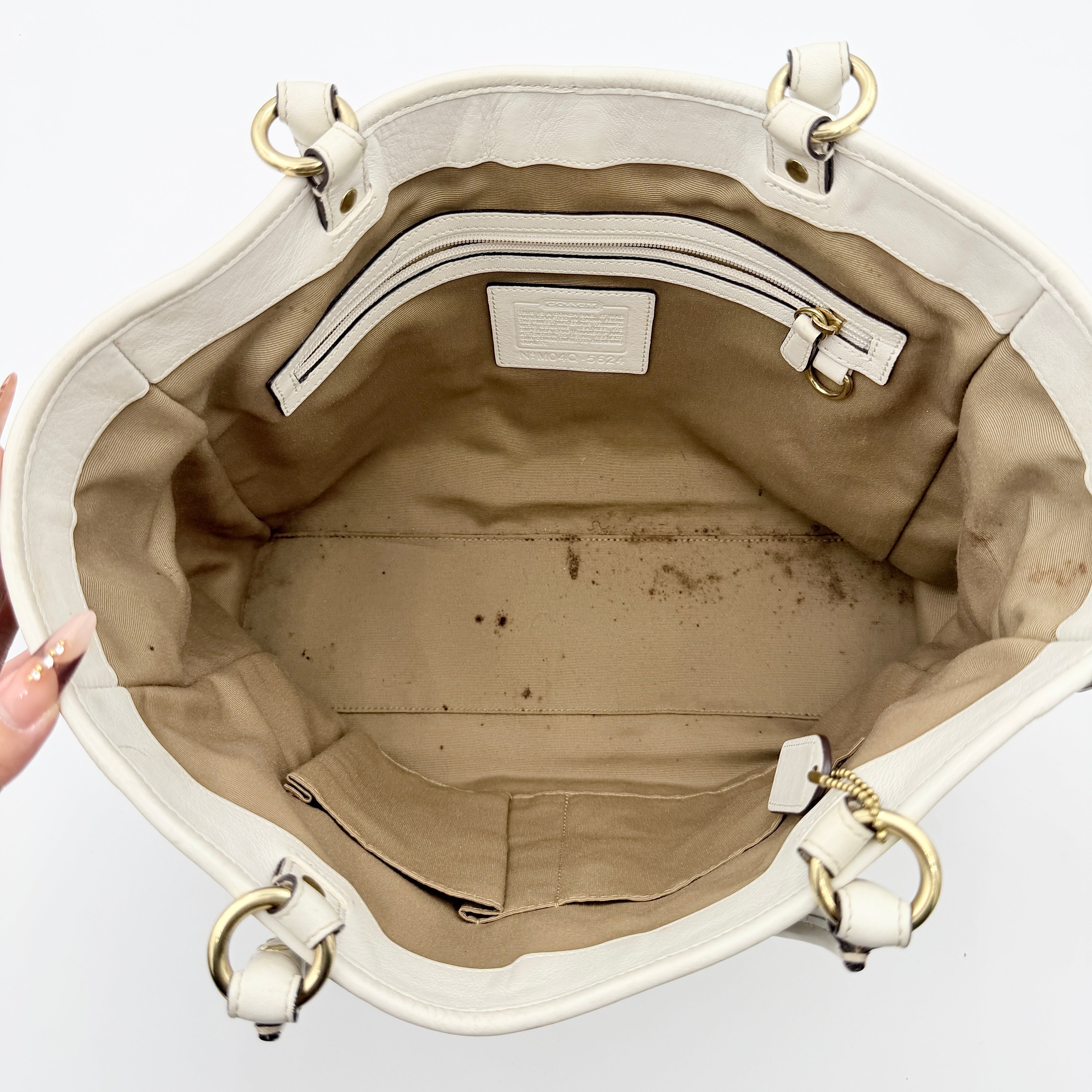 Coach Signature Soho Buckle Tote in beige canvas with white leather trim and gold-tone hardware, displayed against a clean background.
