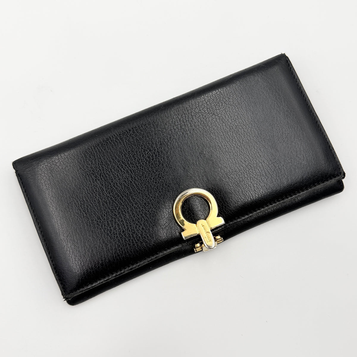 Salvatore Ferragamo Gancini Continental Wallet in black leather with gold-tone Gancini clasp, photographed closed on a white background.