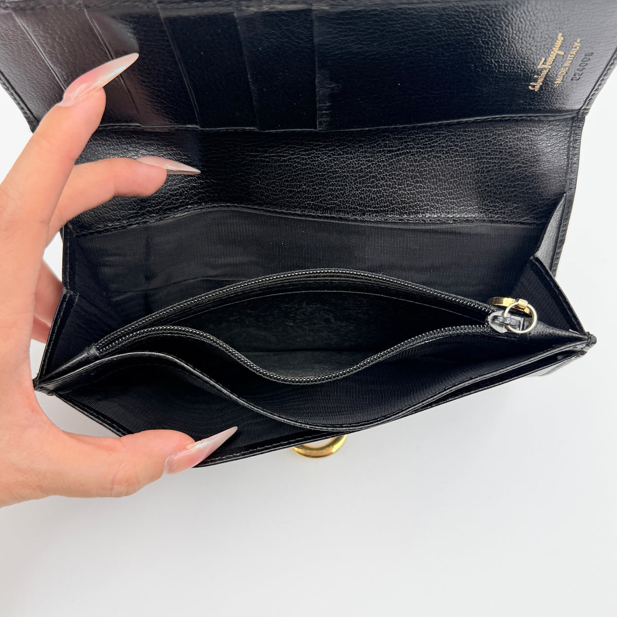 Salvatore Ferragamo Gancini Continental Wallet in black leather with gold-tone Gancini clasp, photographed closed on a white background.