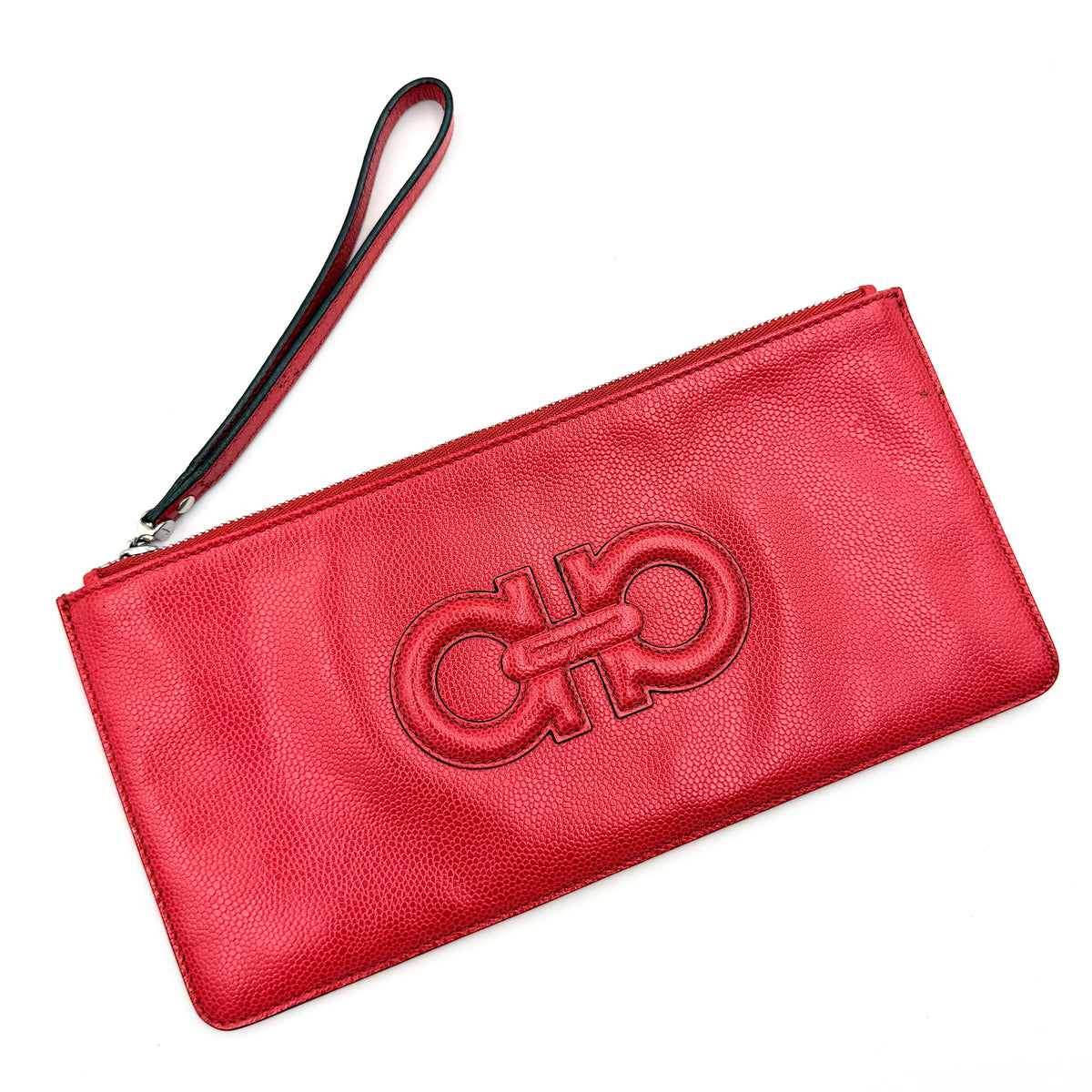 Salvatore Ferragamo red embossed leather wristlet with Gancini motif and wrist strap, shown against a white background.
