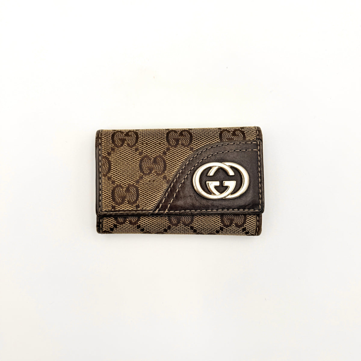 Gucci GG monogram canvas key case in brown with leather trim and a silver GG emblem on the front.