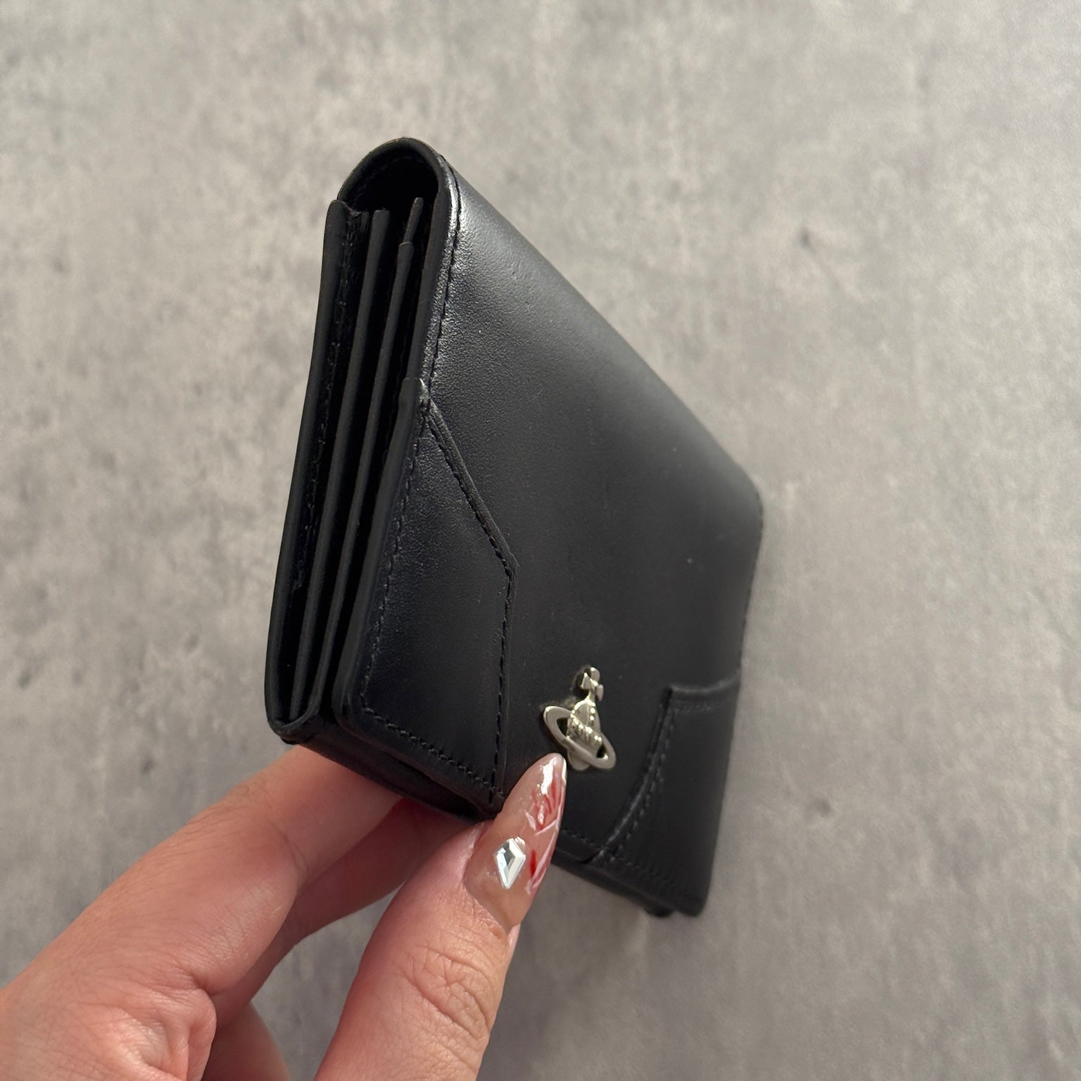 Black Vivienne Westwood cardholder with iconic silver Orb emblem, featuring multiple card slots and a central compartment, perfect for stylish organization.