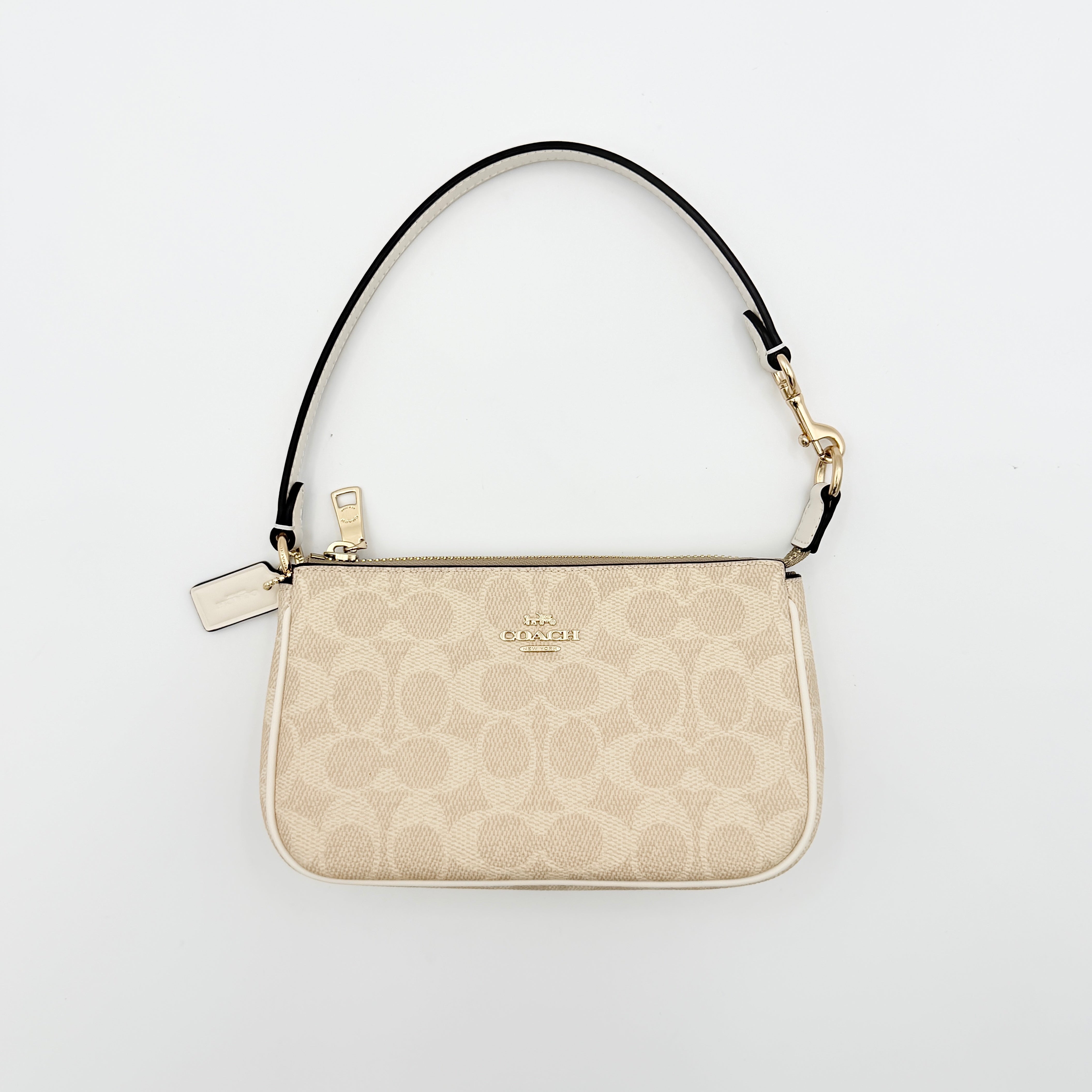 Coach Signature Nolita 19 Shoulder Bag in beige and white canvas with gold-tone hardware and detachable strap, photographed against a plain backdrop.