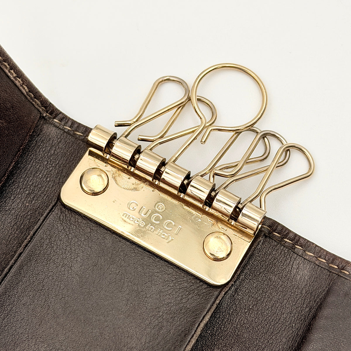 Gucci GG monogram canvas key case in brown with leather trim and a silver GG emblem on the front.
