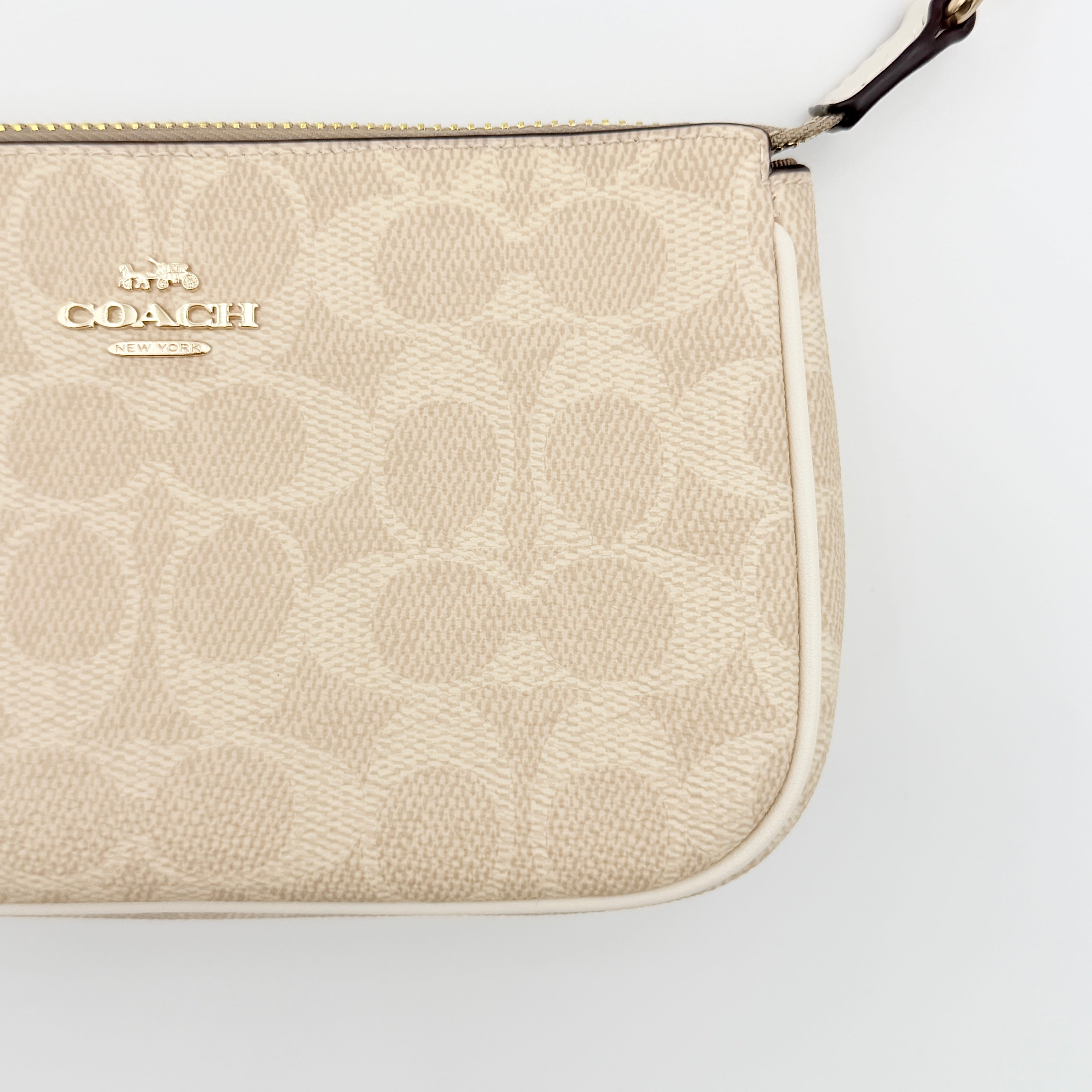 Coach Signature Nolita 19 Shoulder Bag in beige and white canvas with gold-tone hardware and detachable strap, photographed against a plain backdrop.