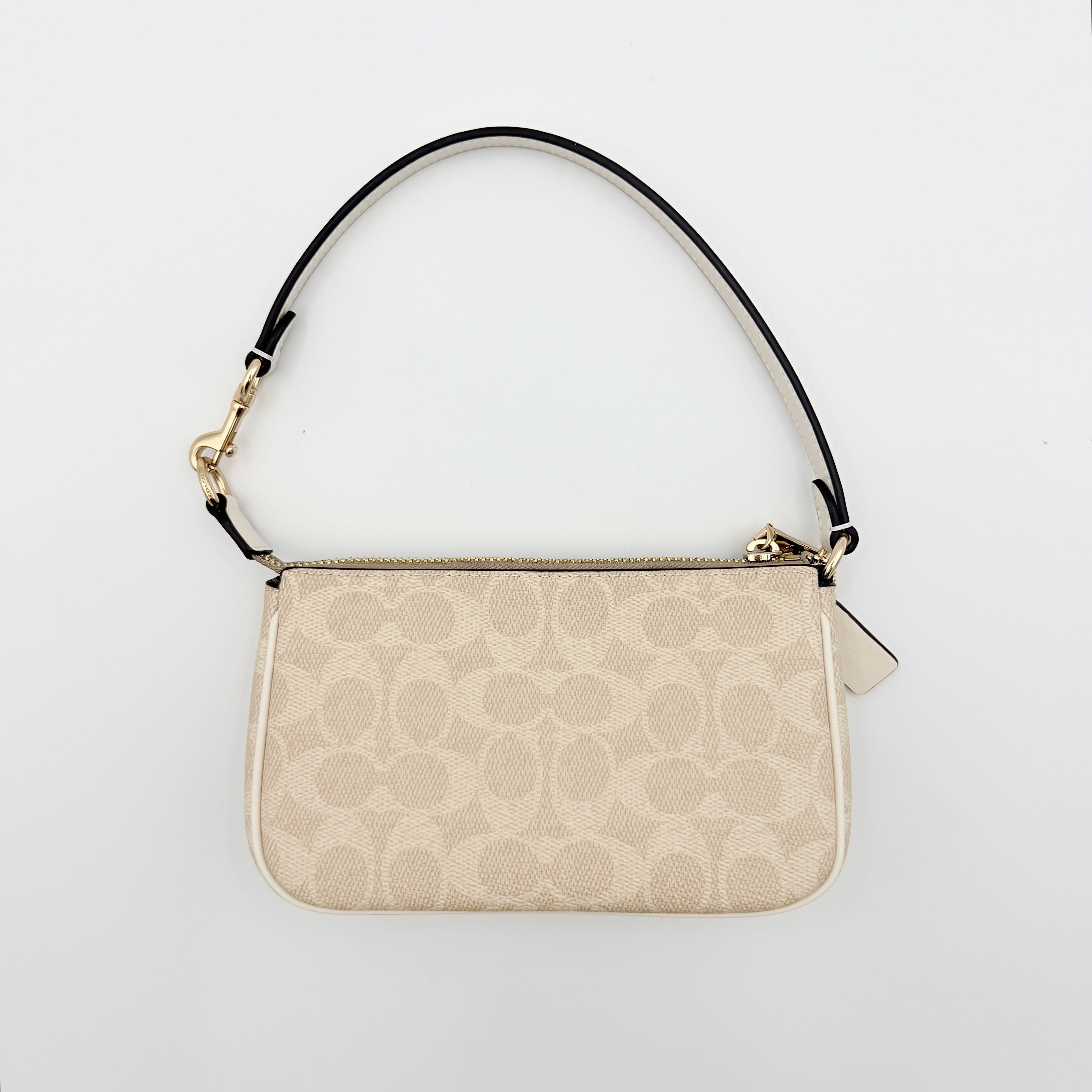 Coach Signature Nolita 19 Shoulder Bag in beige and white canvas with gold-tone hardware and detachable strap, photographed against a plain backdrop.