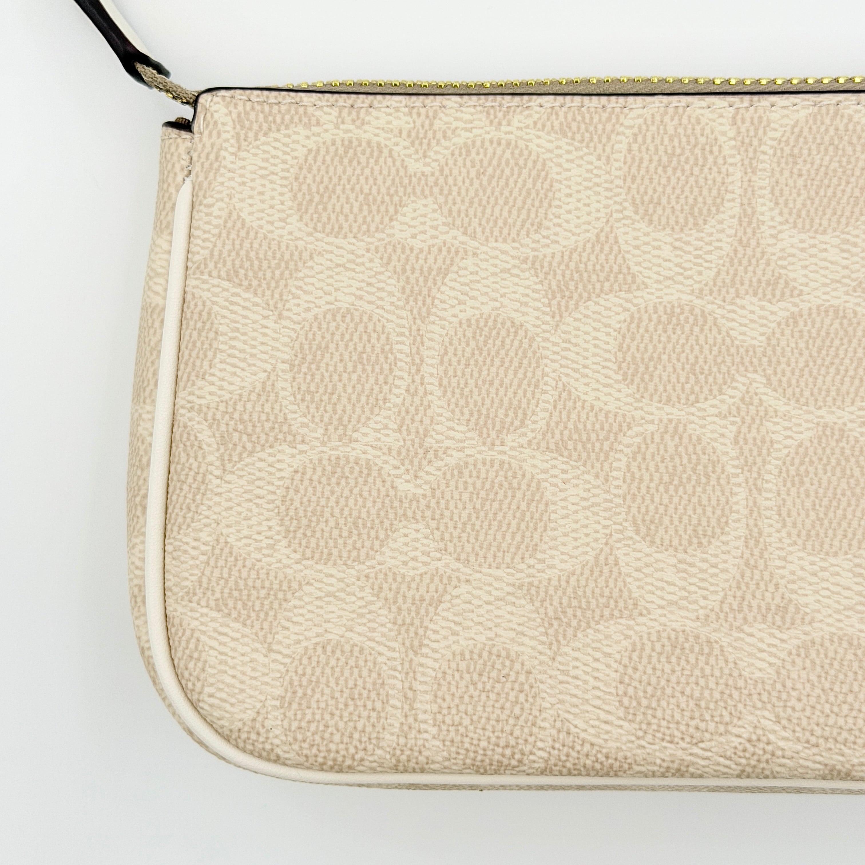 Coach Signature Nolita 19 Shoulder Bag in beige and white canvas with gold-tone hardware and detachable strap, photographed against a plain backdrop.