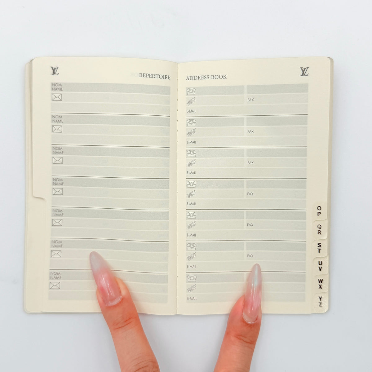 Louis Vuitton Répertoire Address Book in cream with black logo, displayed on a clean white background.