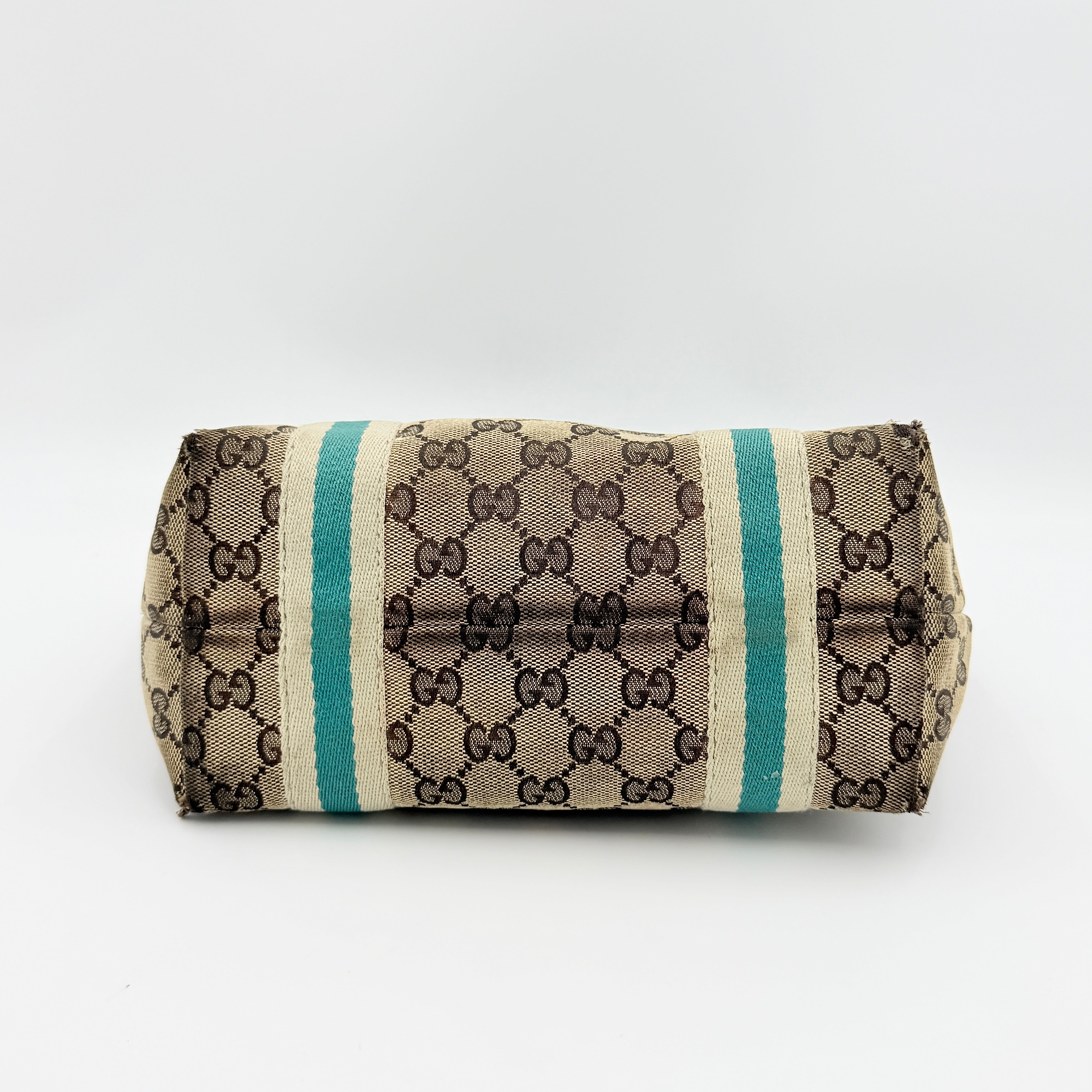 Gucci GG Monogram Jolicoeur Mini Shoulder Bag in beige canvas with teal blue leather trim and gold hardware, shown with a playful charm.