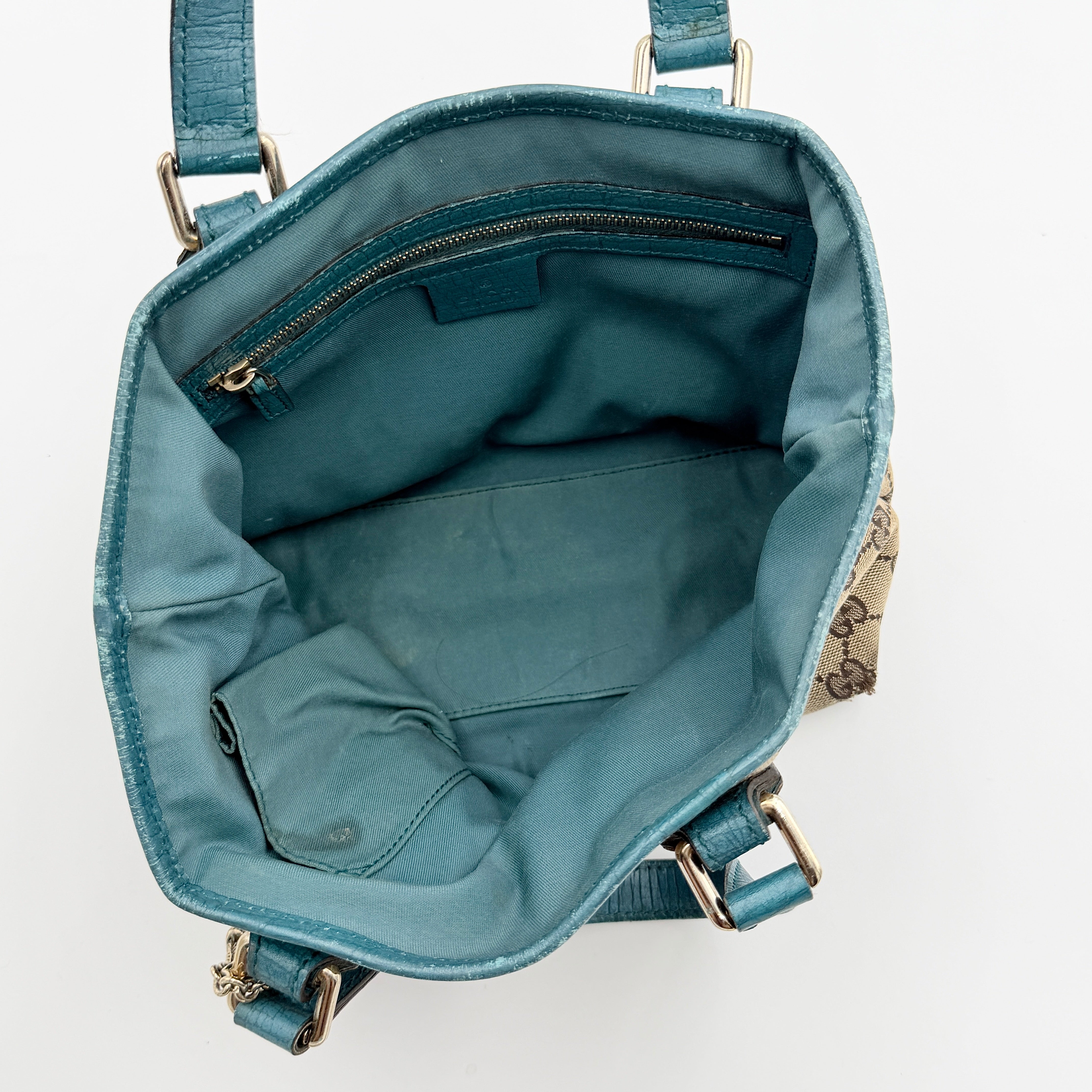 Gucci GG Monogram Jolicoeur Mini Shoulder Bag in beige canvas with teal blue leather trim and gold hardware, shown with a playful charm.