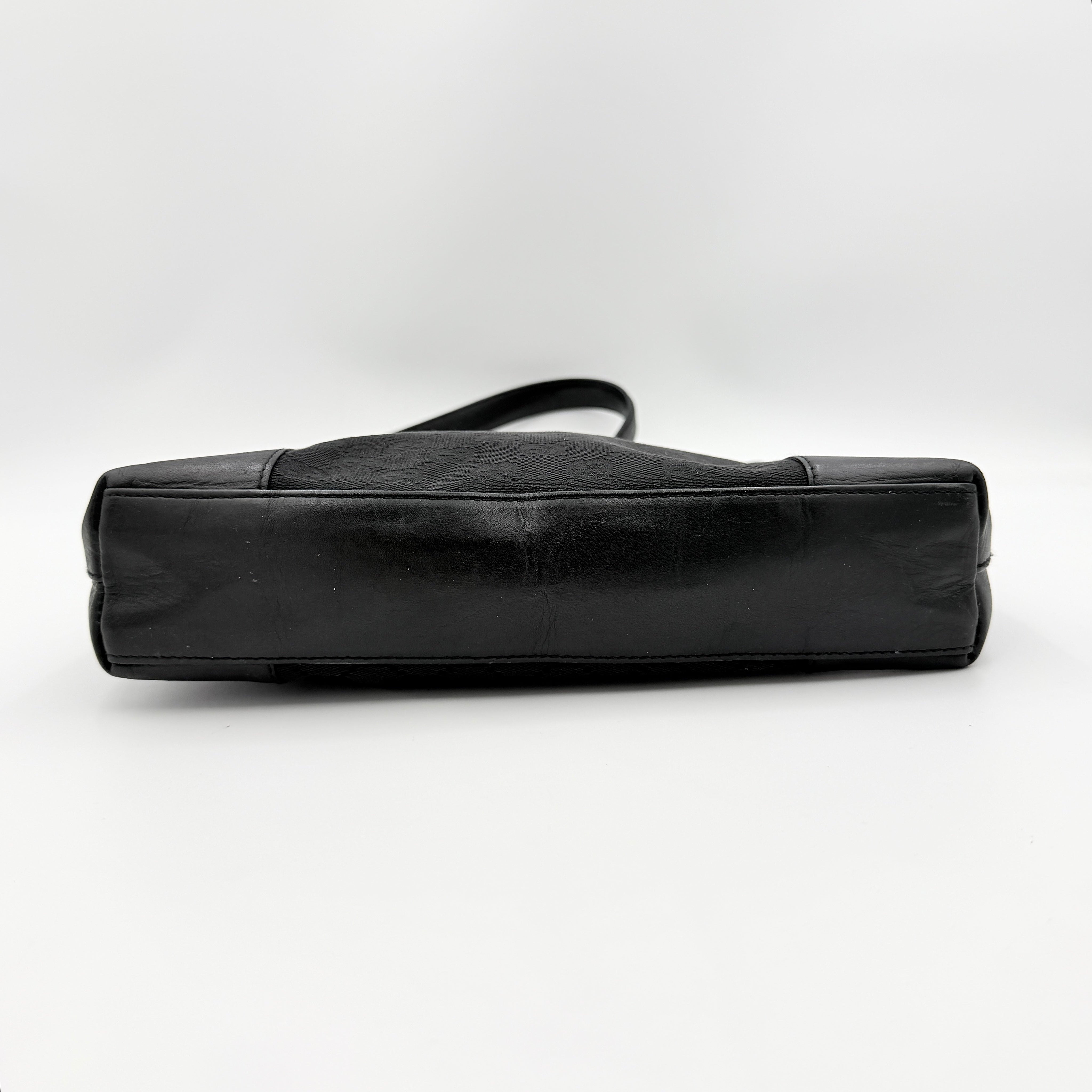 Gucci GG Monogram Bucket Shoulder Bag in black canvas and leather with silver-tone hardware, shown on a white background.